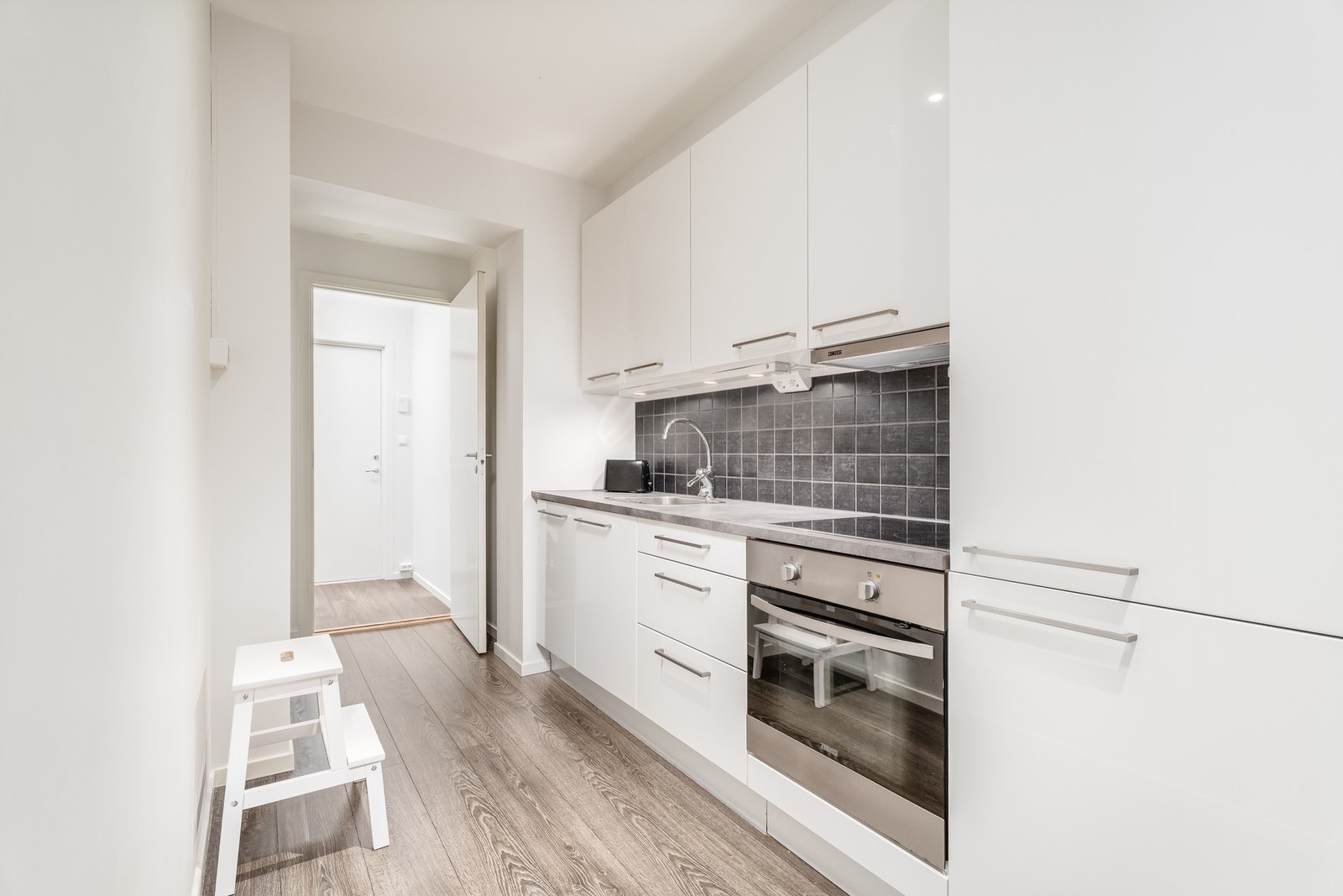 Pent kjøkken fra HTH med integrert kjøl/fryseskap, oppvaskmaskin, platetopp og stekeovn. Galleribilde