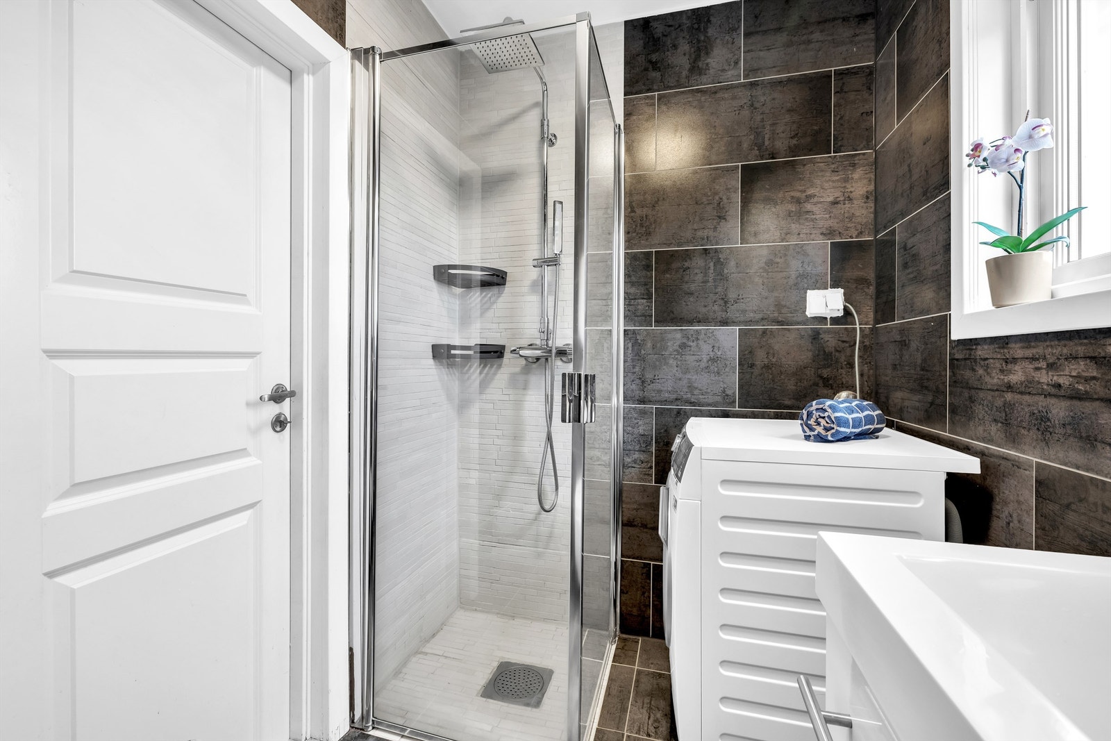 Badet har dusjhjørne med innfellbare dusjvegger, veggmontert toalett samt opplegg og plass til vaskemaskin. Galleribilde