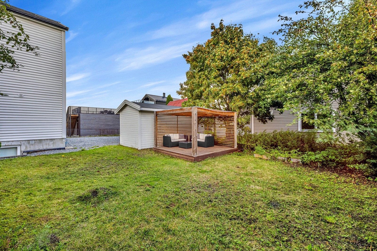 Hagen er ikke seksjonert mellom enhetene, men fordeles seg i mellom ved at denne enheten bruker hage mot øst for eiendommen. Her er det satt opp koselig pergola hvor man kan nyte lange sommerdager. Galleribilde