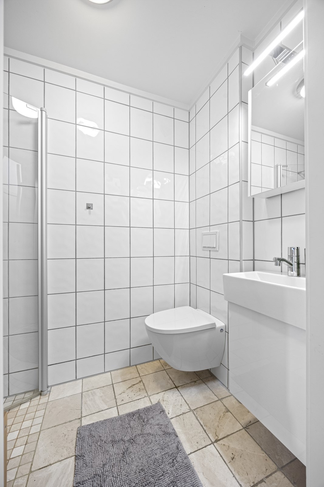 Gjestebad har vegghengt toalett, dusjhjørne og servantinnredning. Galleribilde