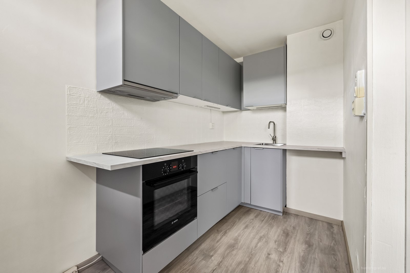 Kjøkkenet har innredning med grå glatte fronter. Benkeplaten er av laminat. Galleribilde