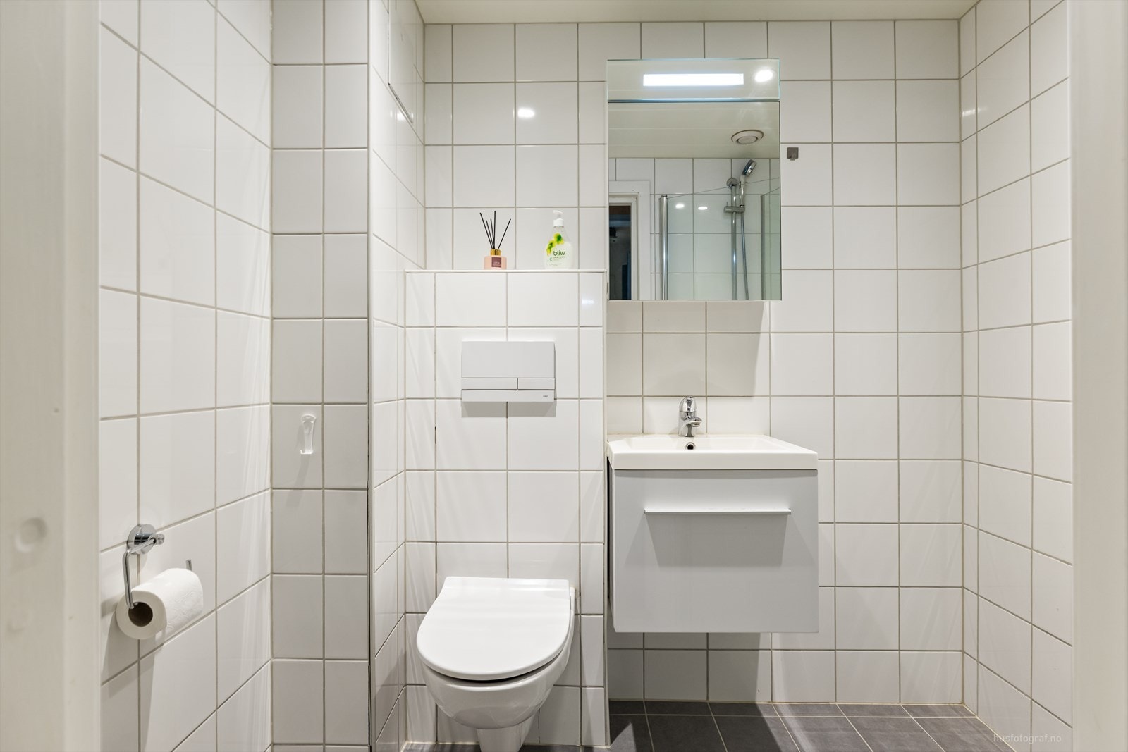 Badet inneholder: toalett, dusjhjørne, servant, speil, belysning og varmekabler i gulv. Galleribilde