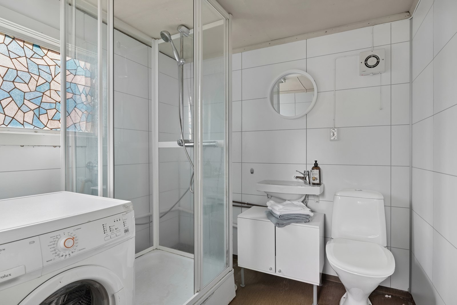 Baderommet er utstyrt med servant med gulvstående skap under, toalett og dusjkabinett. Det er også opplegg for vaskemaskin, noe som gir praktiske vaskemuligheter. Ventilasjonen består av en elektrisk styrt vifte, men rommet mangler tilluftsventilering. Galleribilde