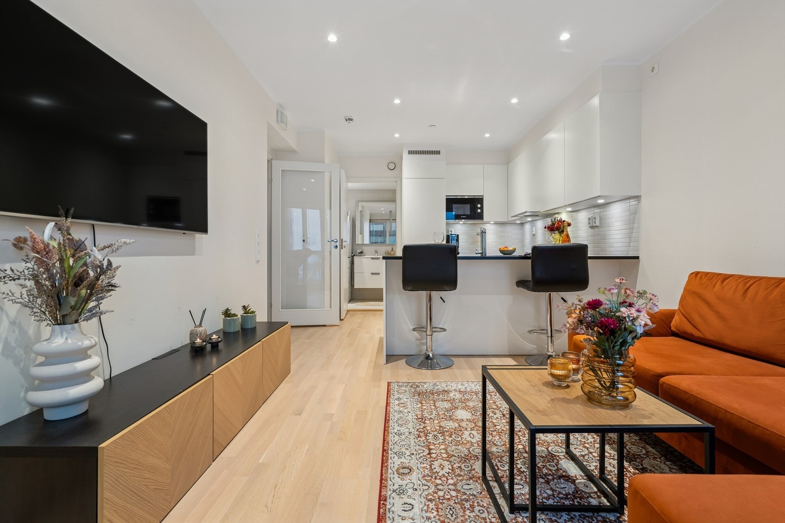 Stue og kjøkken ligger i moderne åpen løsning - Rommet er utført med et pent gulv, lysmalte overflater og utstrakt bruk av downlights i himlingen Galleribilde