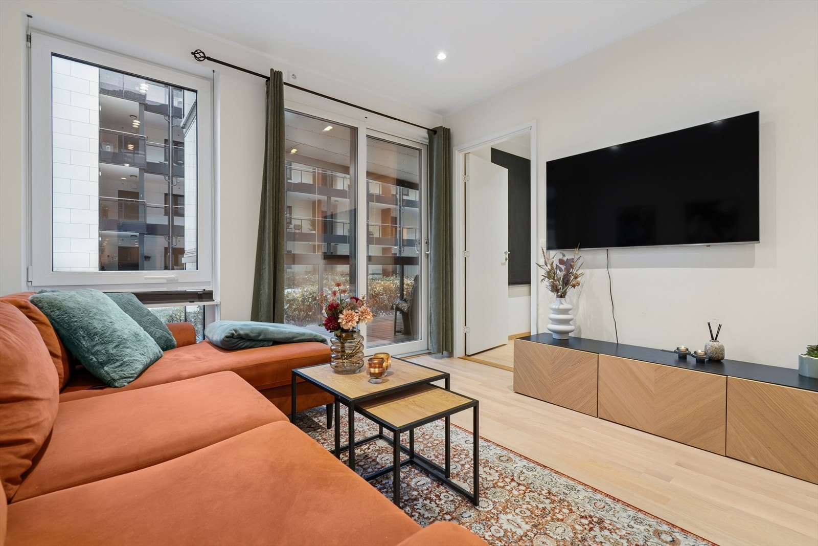 Stuen har store vindusflater som slipper inn rikelig med dagslys og utgang til den innglassede balkongen via skyvedør Galleribilde