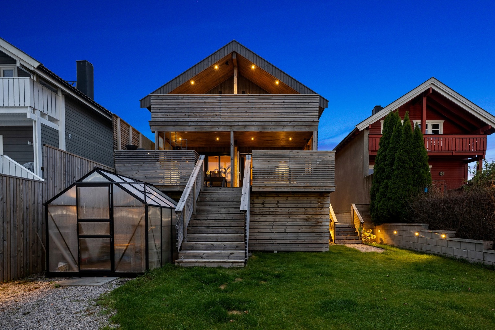 Huset har flotte fasader og lettstelt hage med drivhus Galleribilde