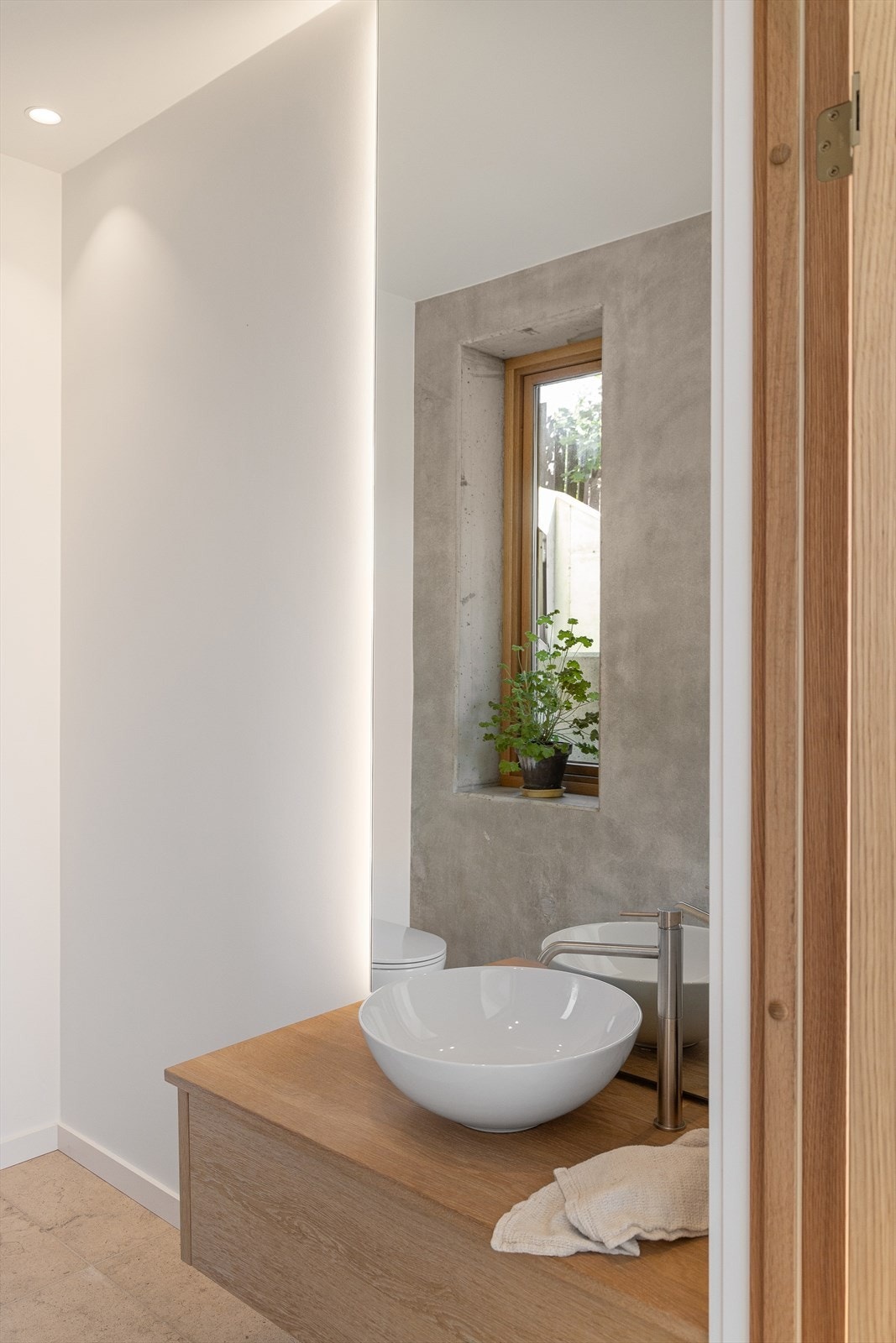 Praktisk toalettrom innredet med servant, plassbygget innredning fra Elen Møbelstudio, speil med belysning og vegghengt toalett Galleribilde