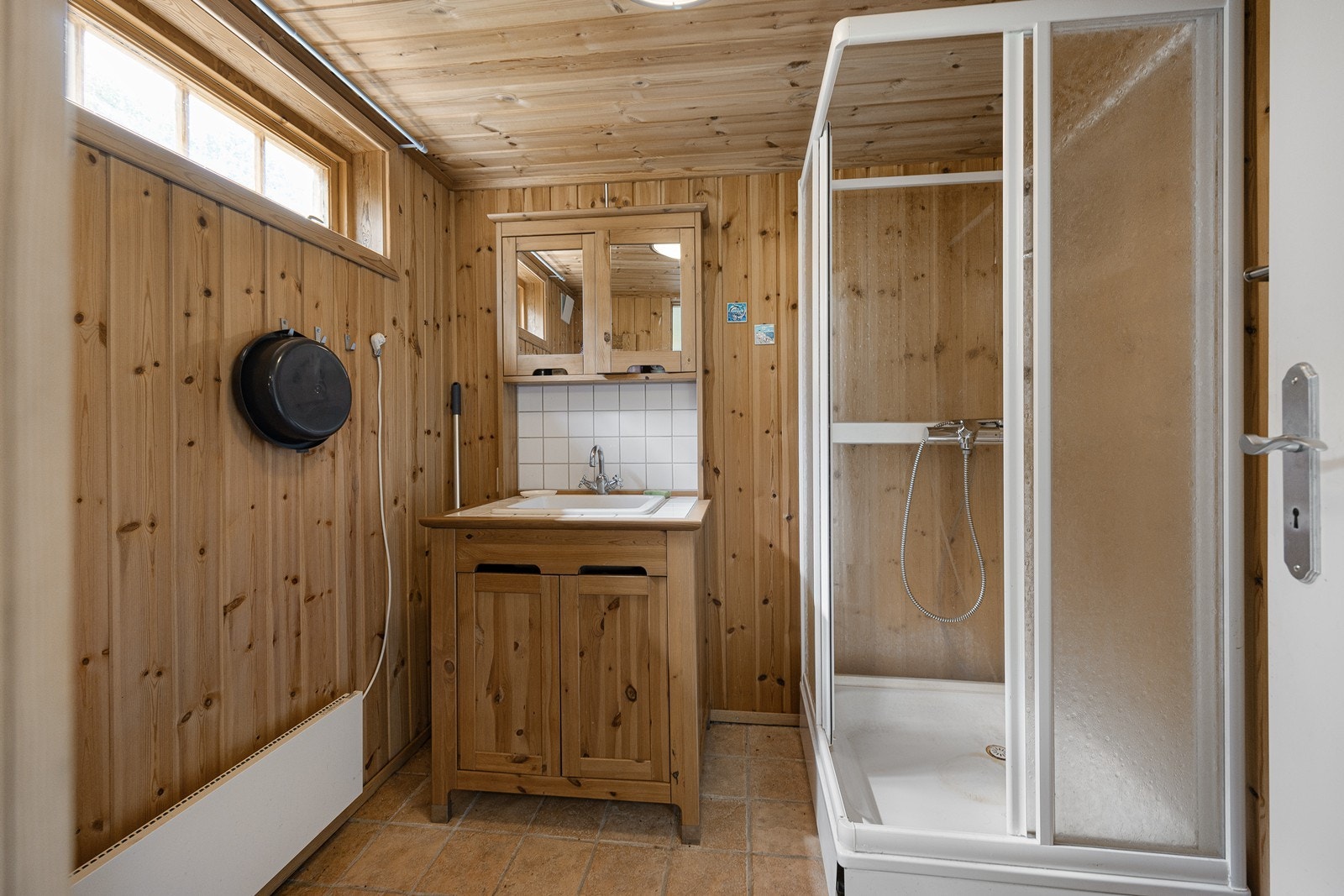 Badet har lyse gulvfliser med gulvvarme. Innredningen m/profilerte heltrefronter, nedfelt servant i skapseksjon og dobbelt speilskap. Videre har badet et dusjkabinett. Galleribilde