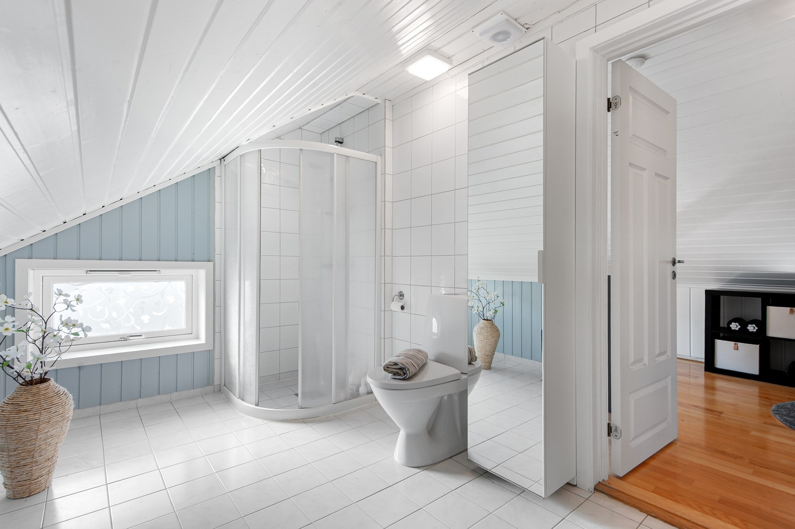 Det er utstyrt med dusjhjørne med buede dører, toalett og servant. Galleribilde