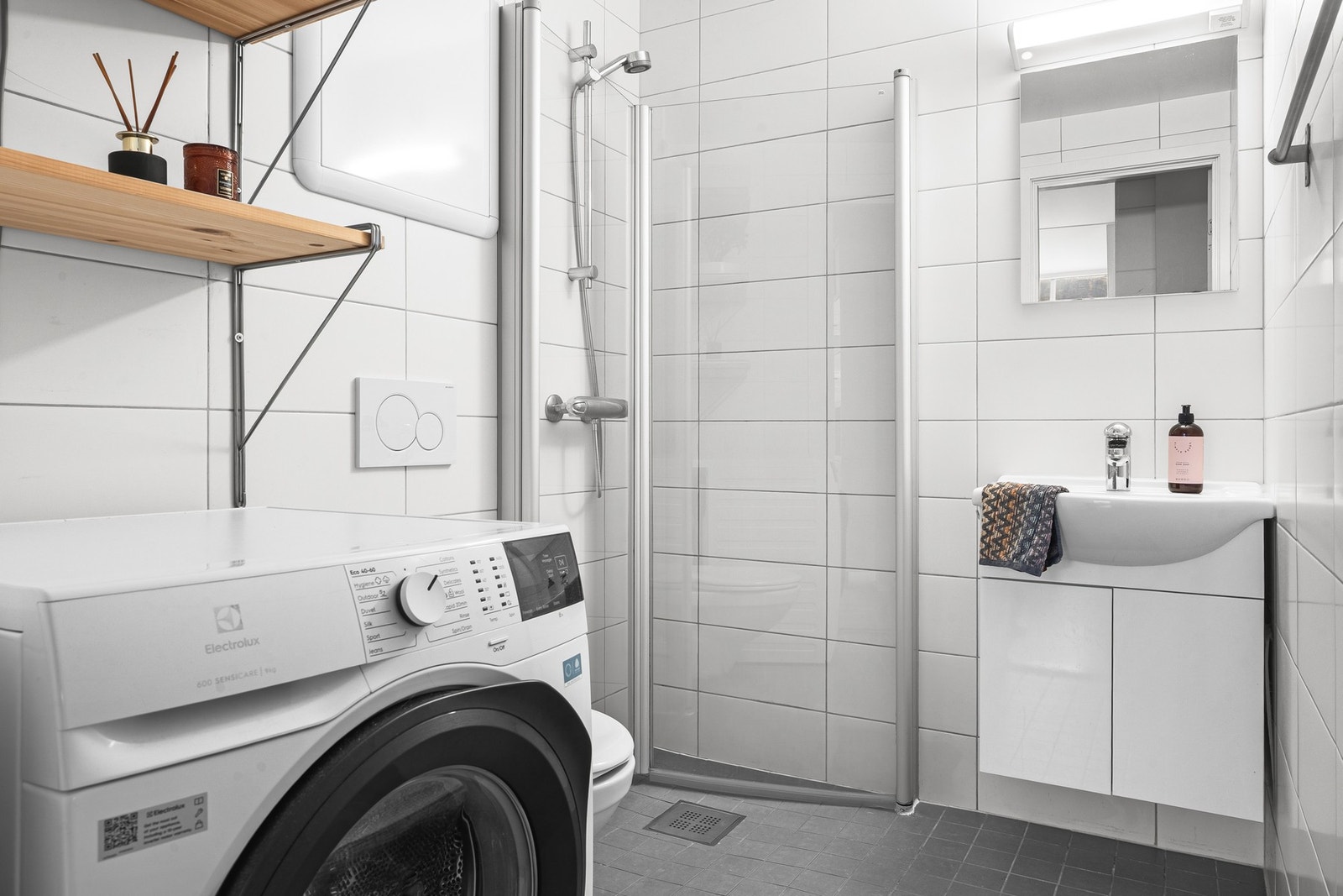 Det helflisede badet har et moderne uttrykk med lyse fliser og tidsriktige detaljer. Galleribilde