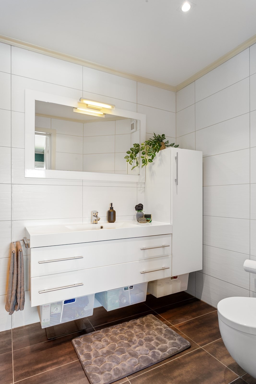 Badet fremstår moderne og stilrent med flislagte vegger og flislagt gulv med elektriske varmekabler. Taket er malt og har integrerte downlights. Galleribilde
