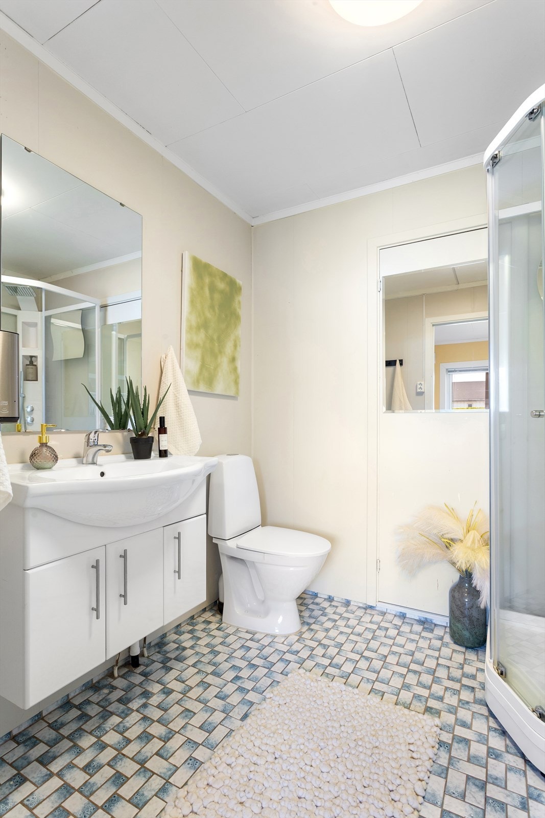 Badet i 1. etasje er eldre, men funksjonelt. Innredningen består av servant på underskap med skuffer, toalett og dusjkabinett. Badet burde moderniseres for å møte dagens standard. Galleribilde