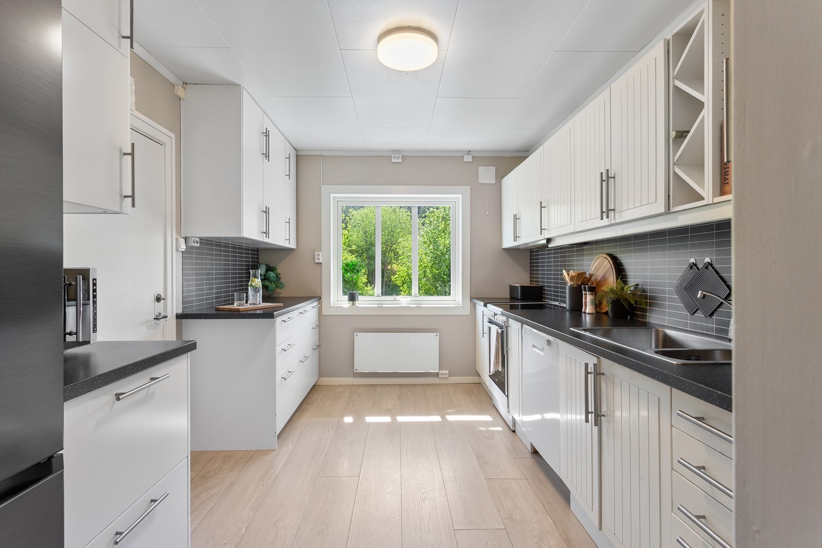 Hybelkjøkkenet er lyst og praktisk, med en kombinasjon av profilerte og glatte fronter samt laminat benkeplate. Galleribilde