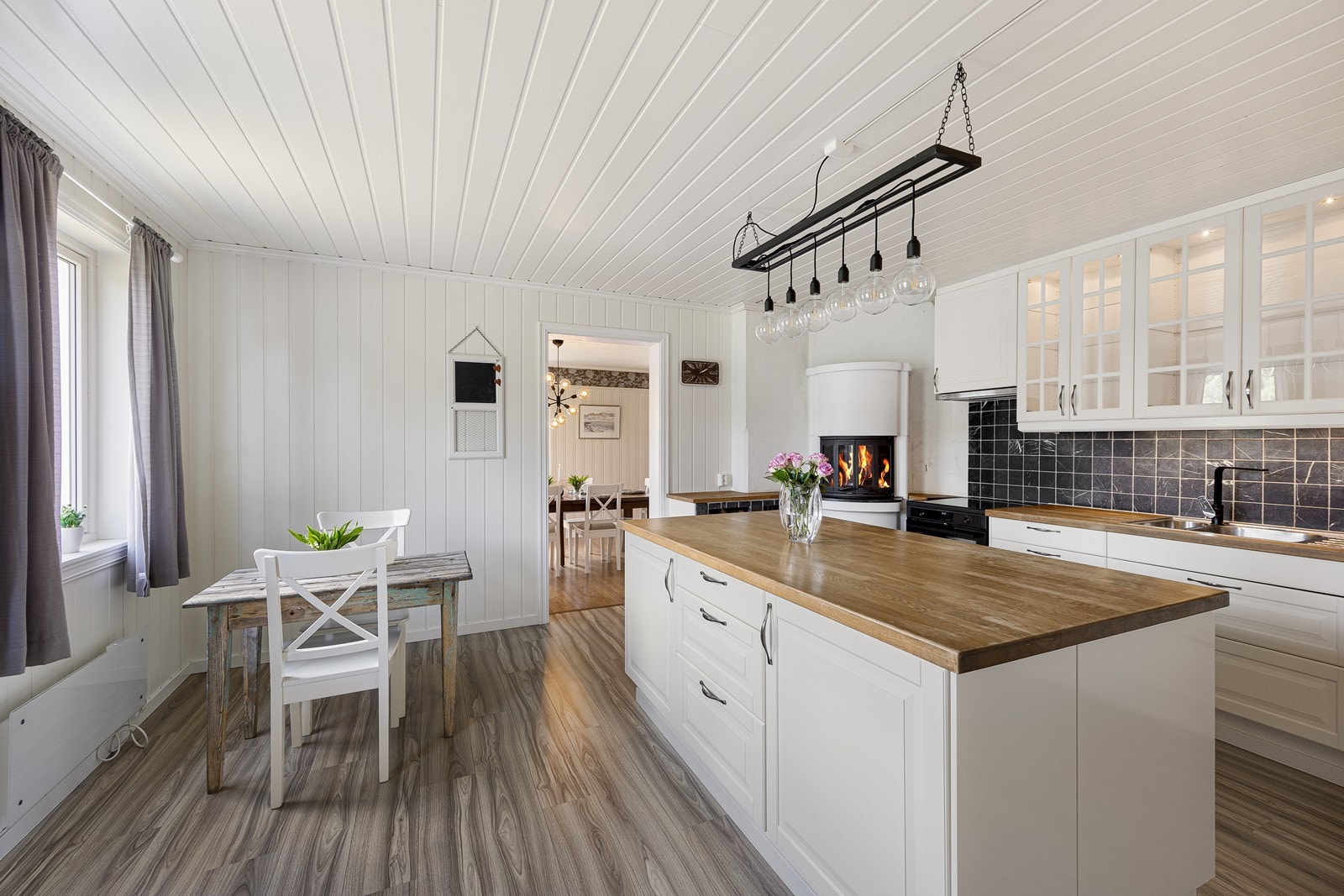 Benkeplaten er i heltre med nedfelt vaskekum i stål og det er lagt mørke, marmorerte fliser over benken. Kjøkkenet har videre hvitmalte paneloverflater og laminatgulv. Galleribilde