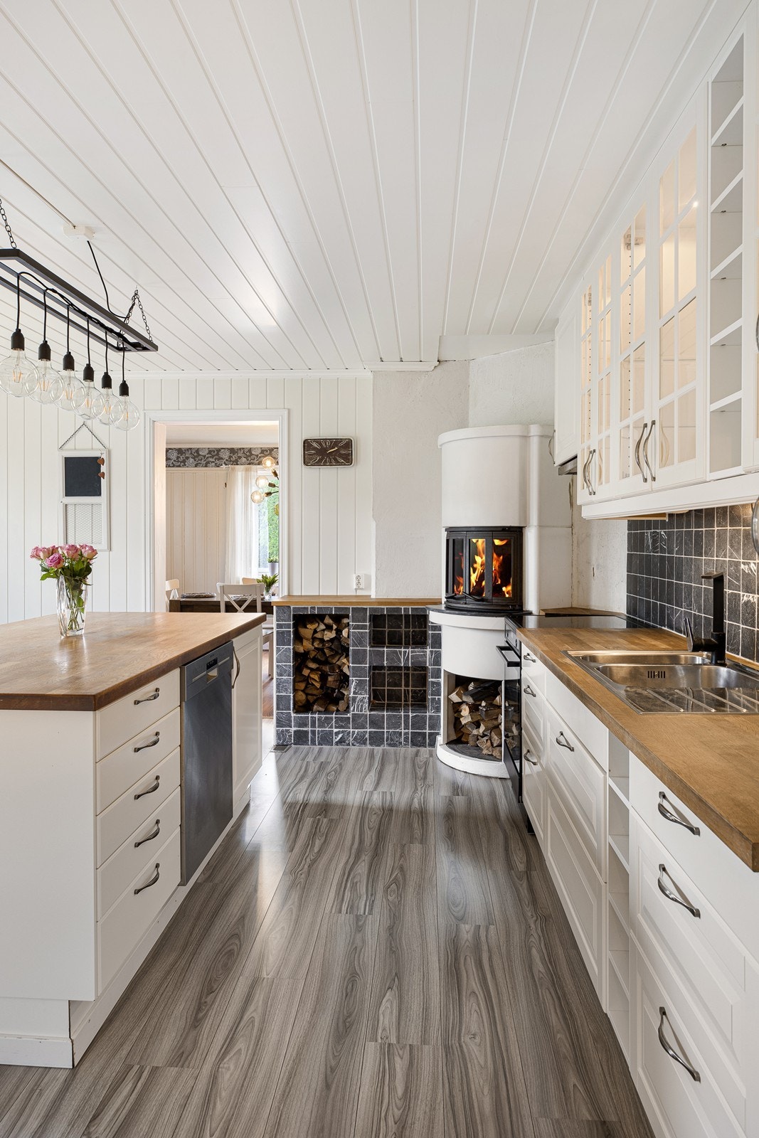 Stilig peisinnsats i benkehøyde på kjøkkenet med stort flammebilde. Galleribilde