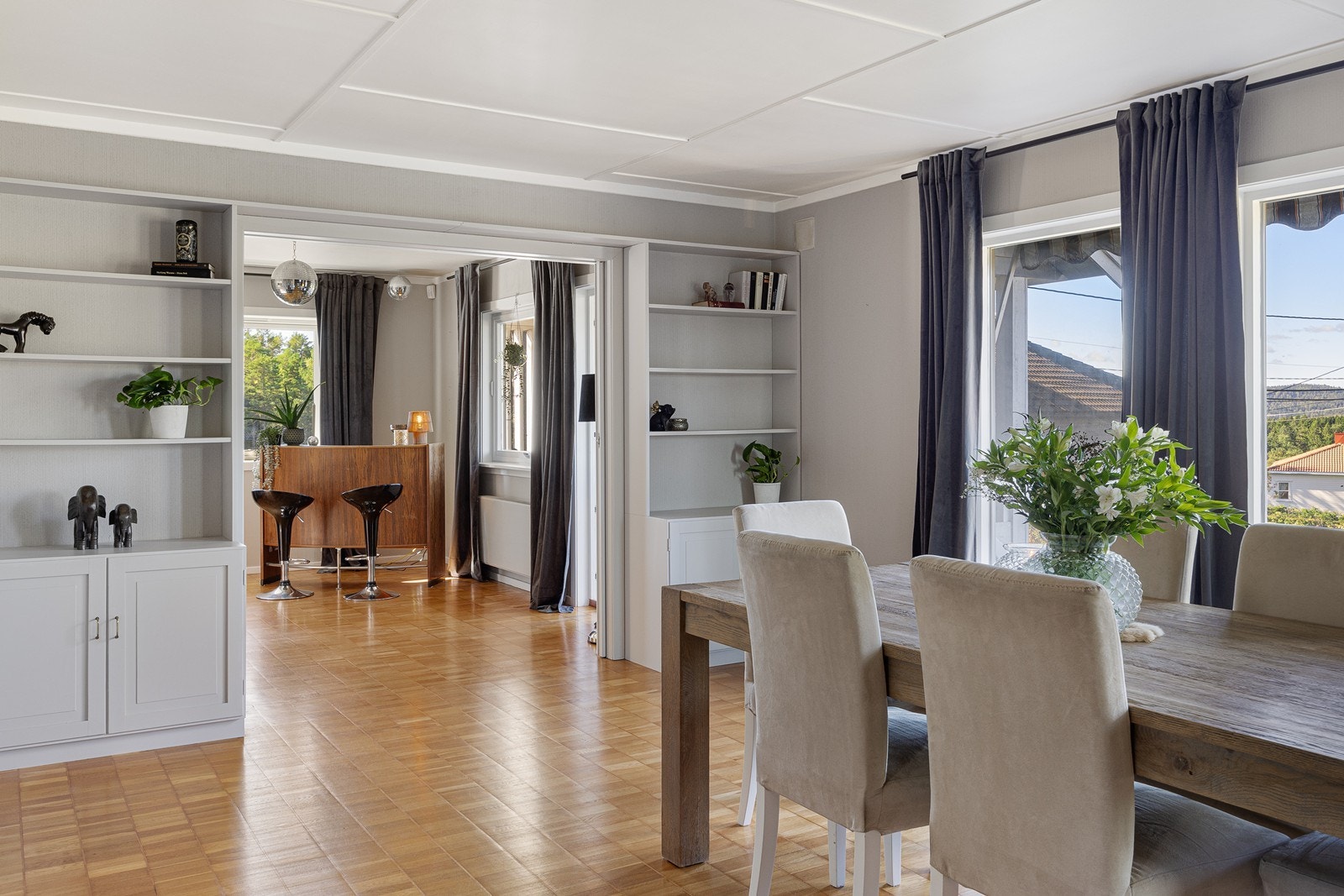 Den innbydende stue er delt inn i tre soner - én tv-stue, én dagligstue med utgang til den takoverbygde verandaen, samt en spisestue. Galleribilde