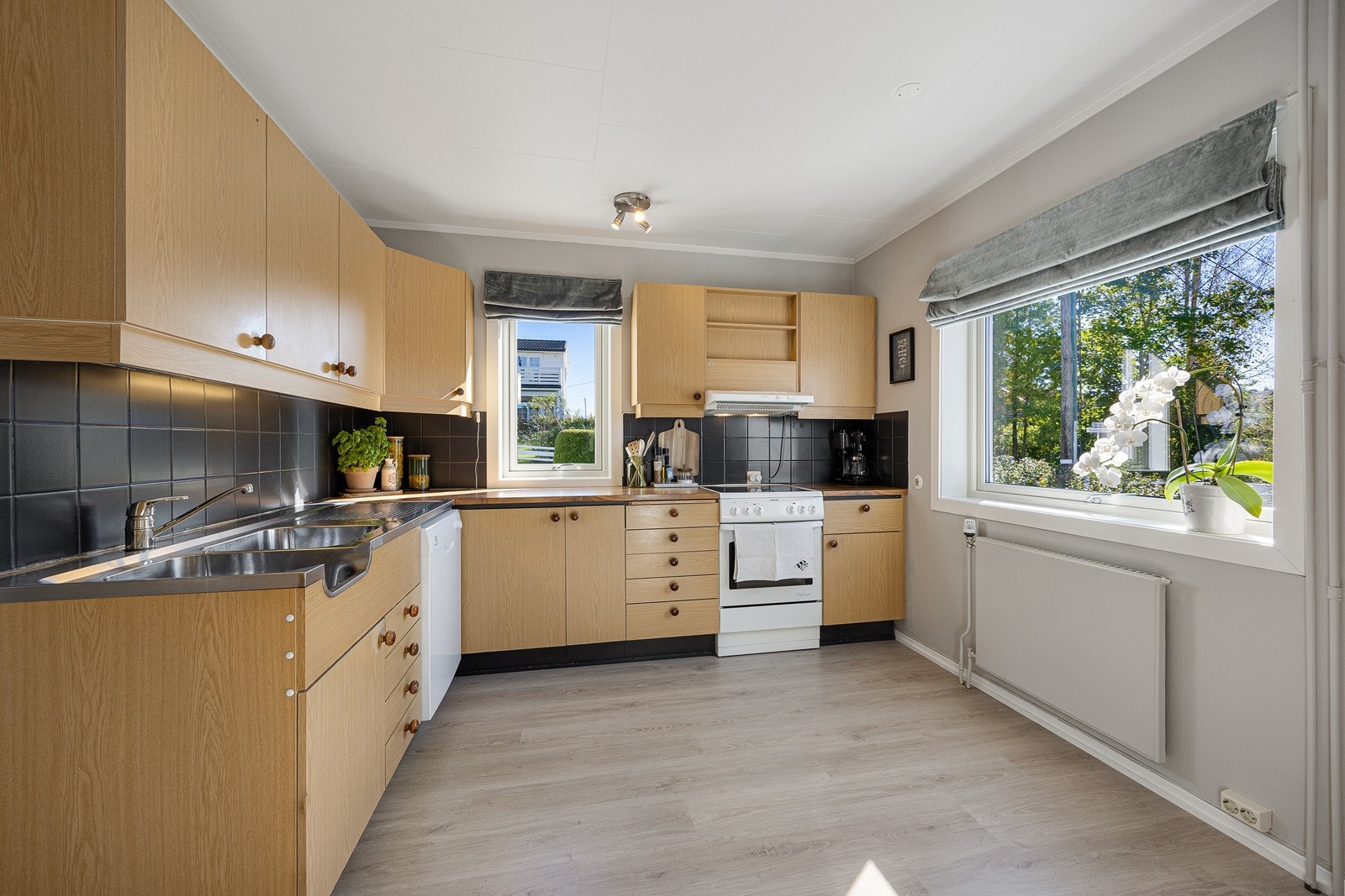 Kjøkkenet har et tidløst design med gode benkeflater og rikelig med oppbevaringsplass. Innredningen har lyse, finerte fronter, laminatbenkeplate og benkebeslag i stål med utslagsvask og oppvaskkum. Galleribilde