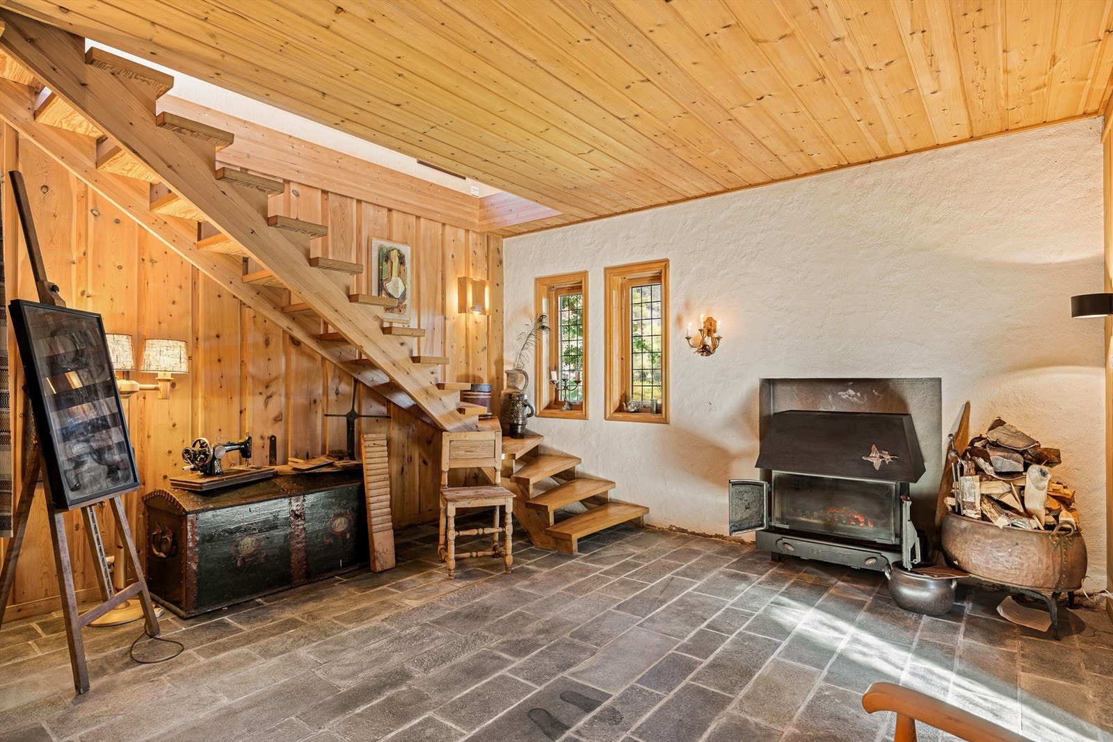 Fra vindfanget kommer du inn en romslig hall som også brukes som kjellerstue. Den solide peisen er fint plassert i en nisje. Galleribilde