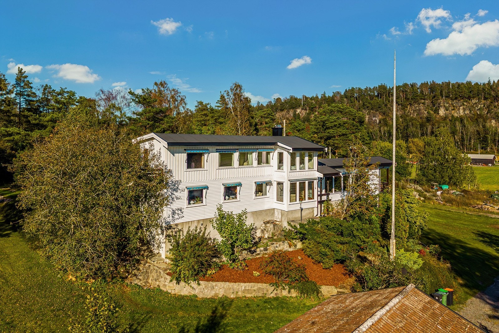 Det hvitmalte trehuset ligger på en liten kolle helt for seg selv på Rogn. Galleribilde