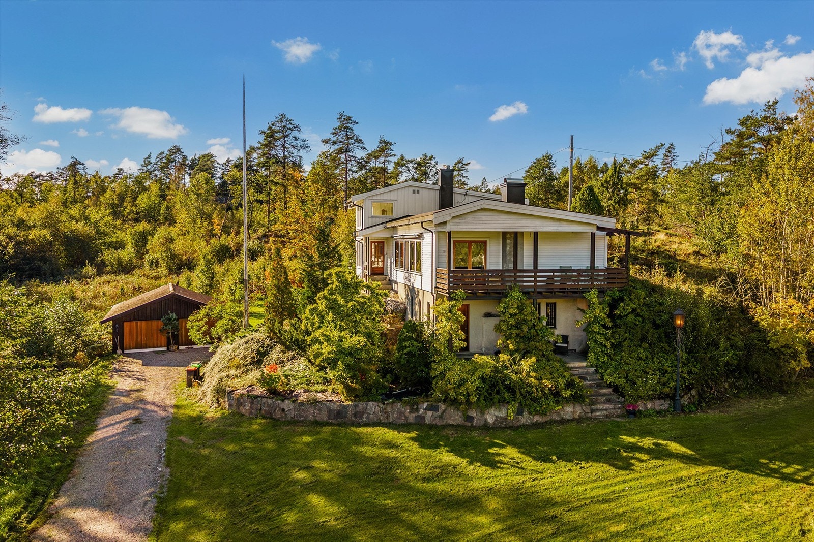 Natursteinsmur, prydbusker og blomsterbed danner en ramme omkring boligen. Galleribilde