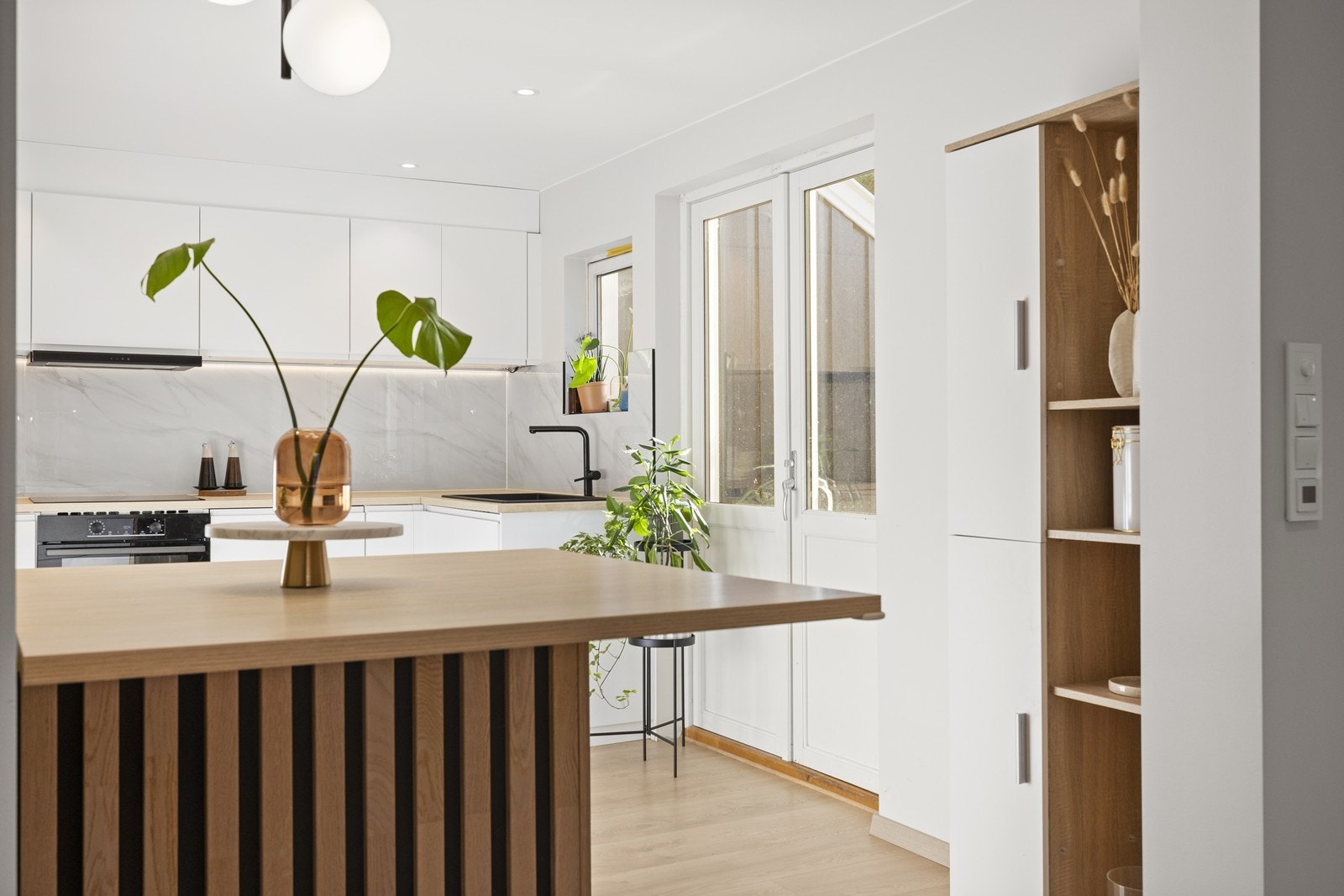 Pent kjøkken i åpen løsning med stue og spisestue. Galleribilde