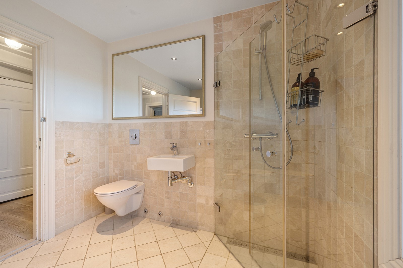 Rommet er innredet med vegghengt toalett, servant og dusjhjørne med innfellbare glassvegger. Galleribilde