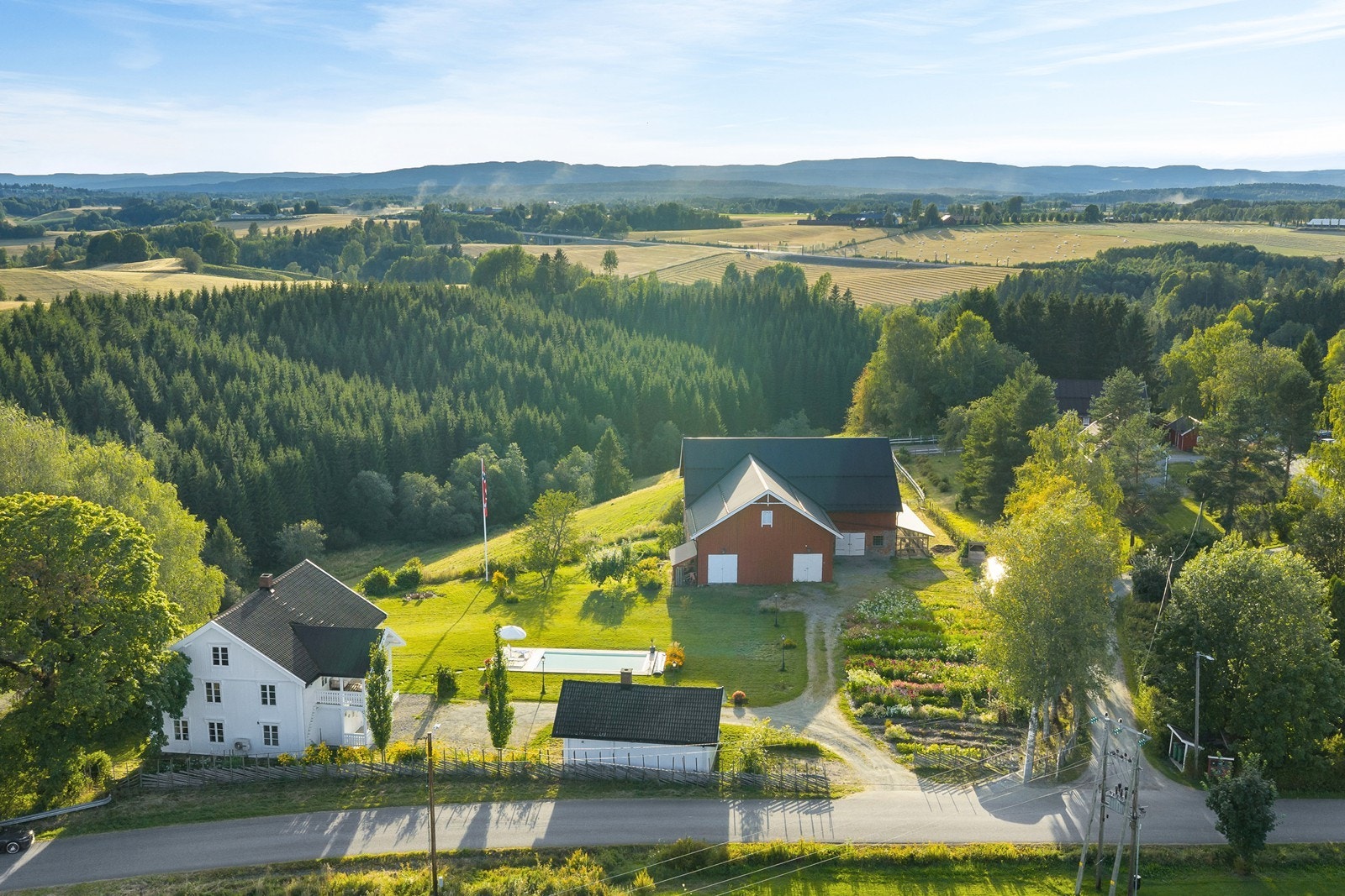 Oversiktsbilde. Det er gruset innkjørsel og parkeringsareal på eiendommen. Galleribilde
