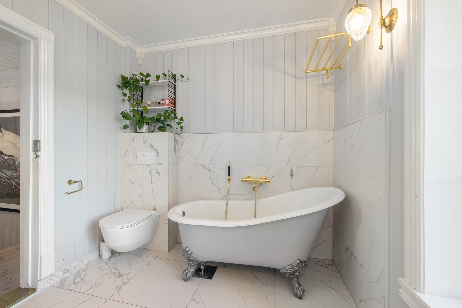 Badet er innredet med badekar, servant i baderomsinnredning, dusjhjørne med innfellbare glassvegger og toalett. Galleribilde