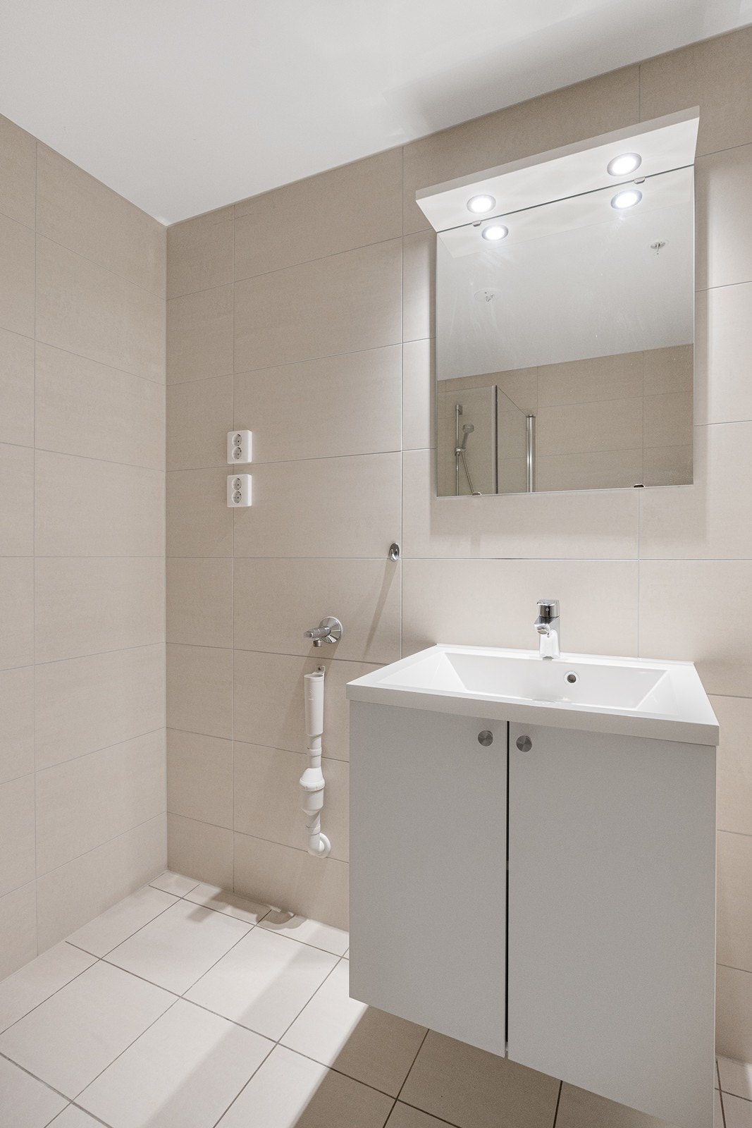 Det flislagte badet har gulv med varme, vegghengt servantskap med tilhørende speil. Galleribilde