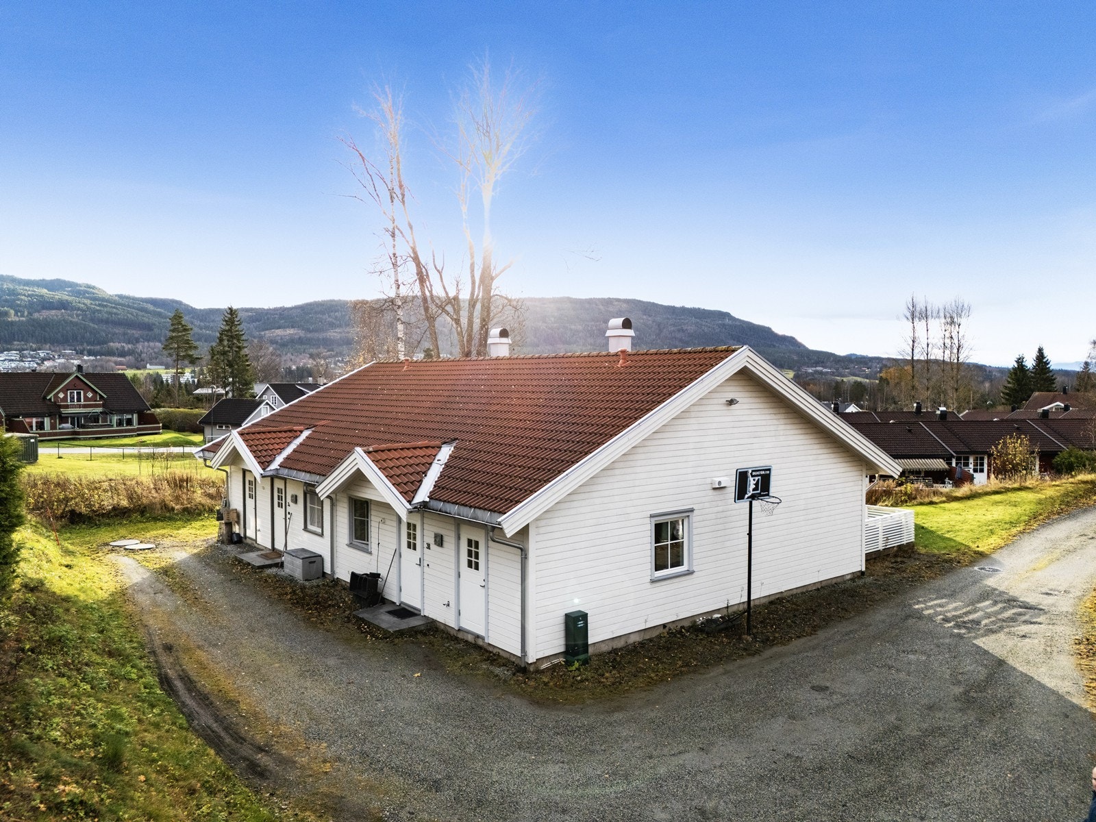 Eiendommen har en felles eiet relativt flat tomt, opparbeidet med plen og gruset gårdsplass. Galleribilde