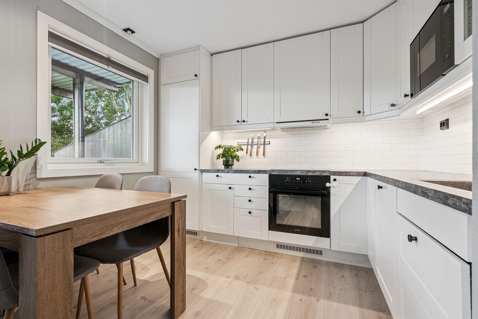 Kjøkkeninnredningen i vinkel byr på lyse og slette overflater, samt integrerte hvitevarer. Galleribilde