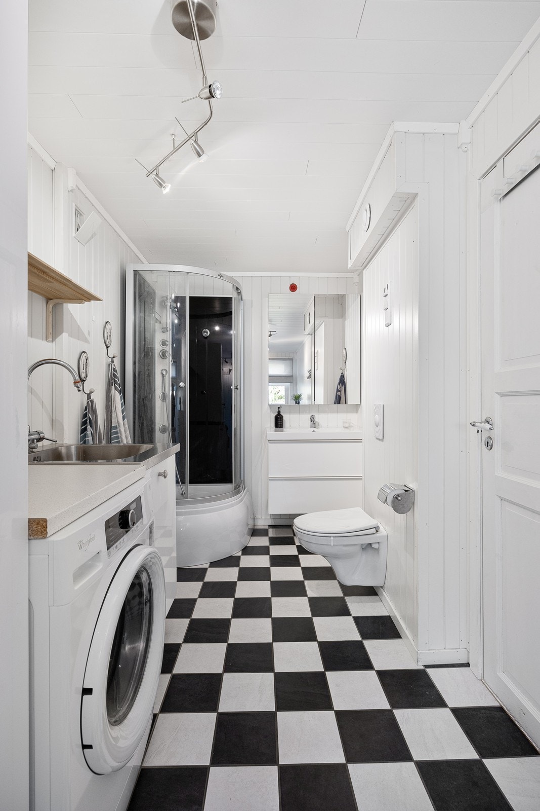 Badet har flislagt gulv i sjakkmønster, lysmalte panelvegger og gulvvarme. Galleribilde