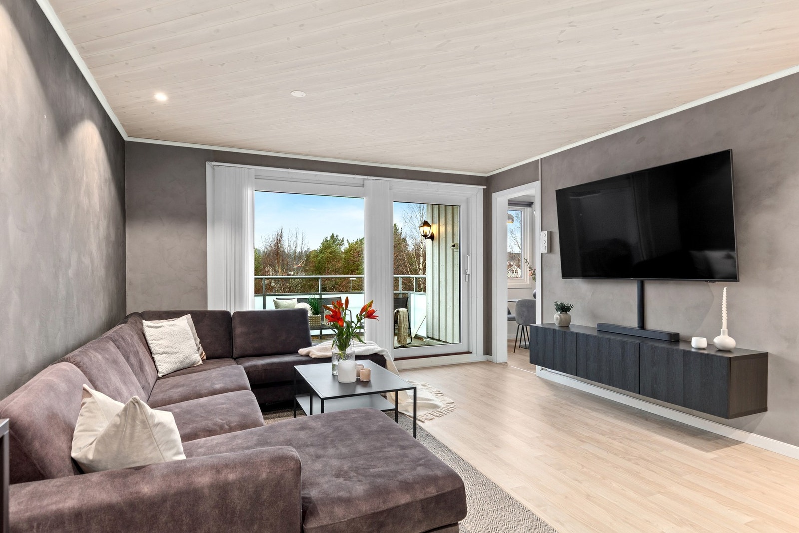 Stue med downlights i himling og rikelig innslipp av naturlig lys fra vinduer. Det er lagt opp solskjerming på vinduene på balkong. Styres via fjernkontroll. Galleribilde