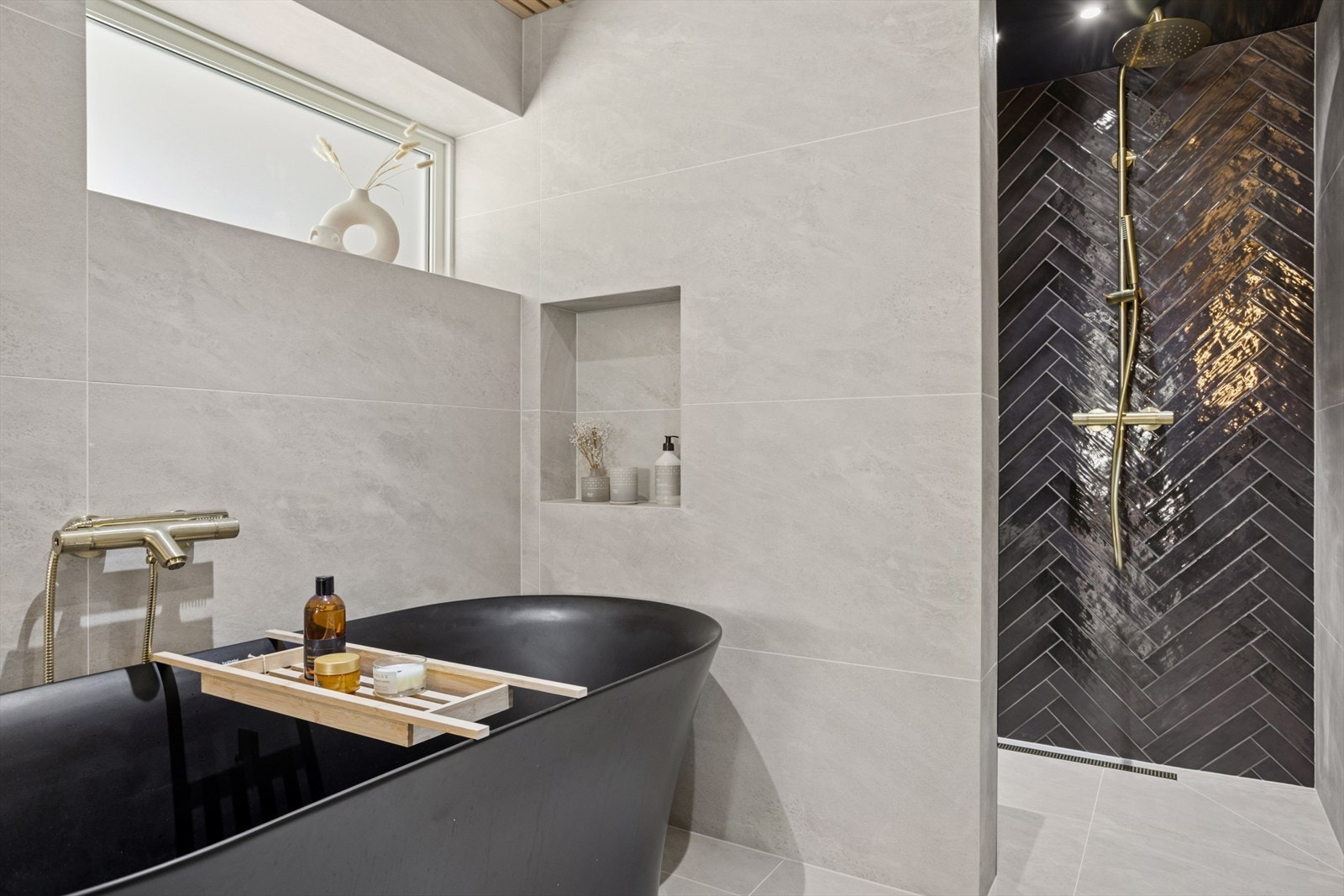 Gulvet er belagt med elegante keramiske fliser, mens veggene kombinerer keramiske fliser med spileplater i heltre eik - en varm og naturlig kontrast som gir rommet karakter.
Lekkert badekar - perfekt for lange, avslappende kvelder. Galleribilde