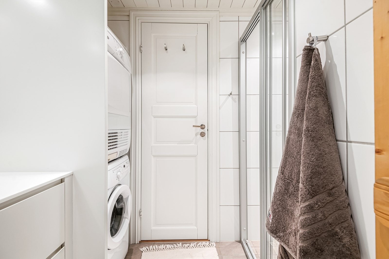 Baderom innredet med dusjnisje med skyvedører i glass, samt nisje for vaskemaskin og tørketrommel. Galleribilde