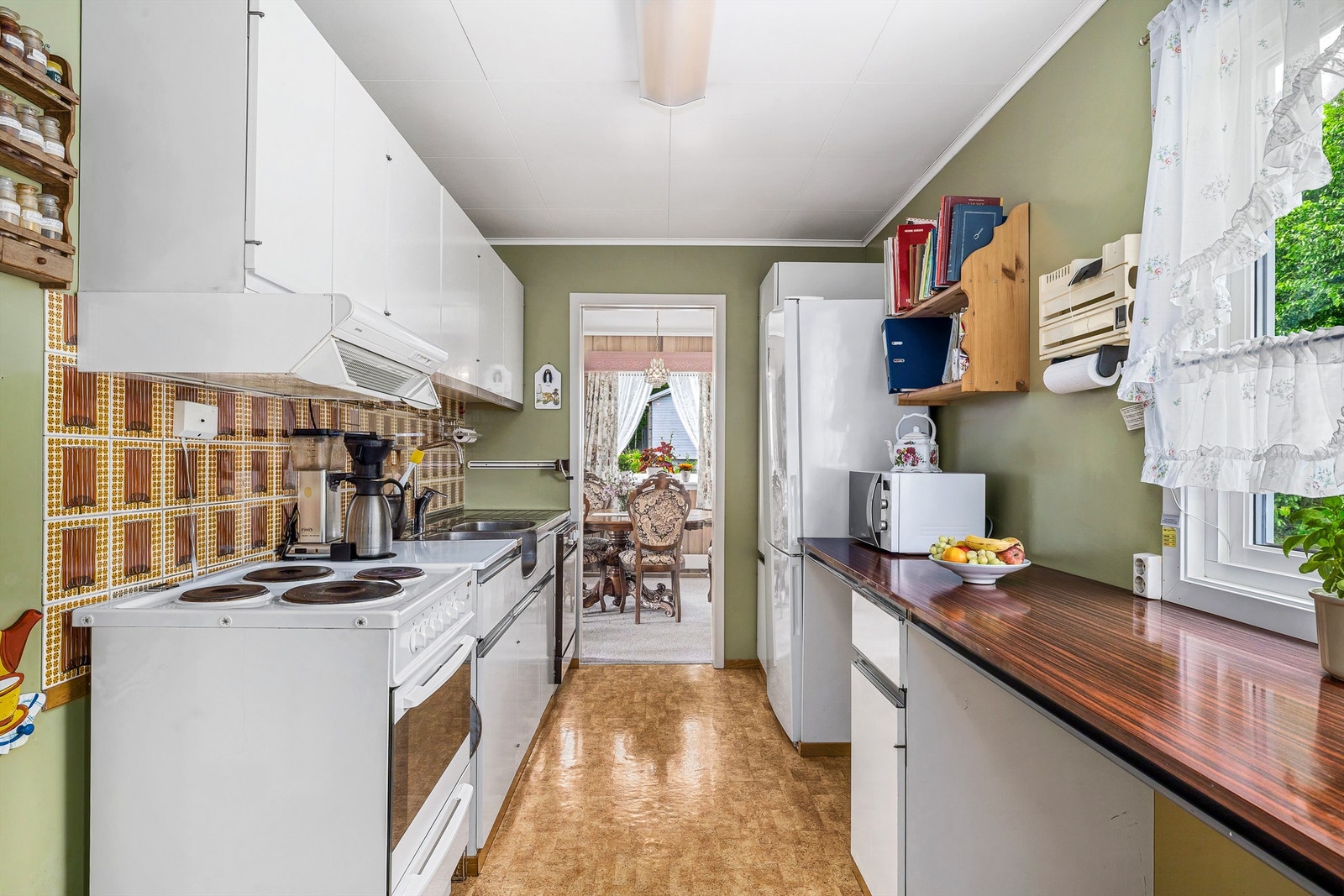 Kjøkkeninnredningen fra byggeår med flis mellom benk og overskap er et riktig arbeidskjøkken med stålvask og god arbeidsbenk. Galleribilde