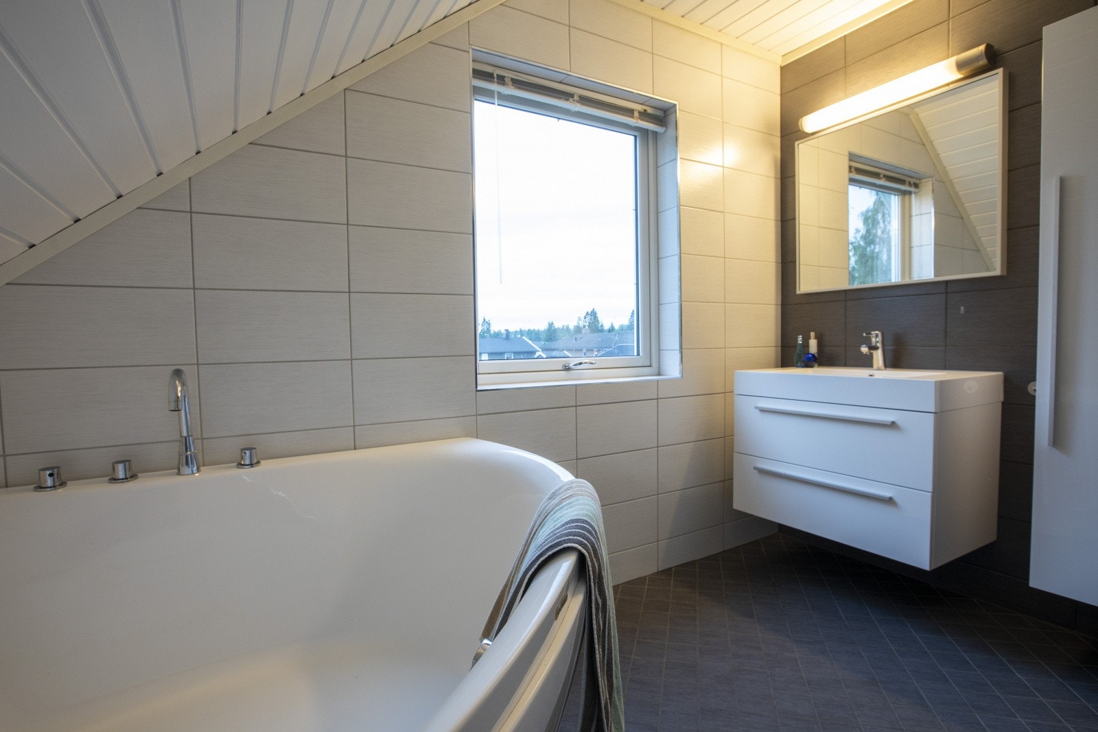 Rommet er innredet med badekar, toalett og servantinnredning med speil og ekstra høyskap. Galleribilde