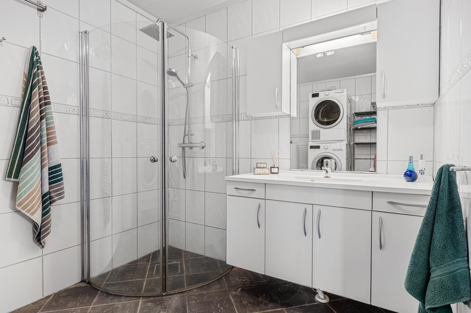 Badet er innredet ,ed dusjnisje med innfellbare glassdører, servantinnredning med speil, toalett og opplegg for vaskemaskin og tørketrommel i søyle. Galleribilde