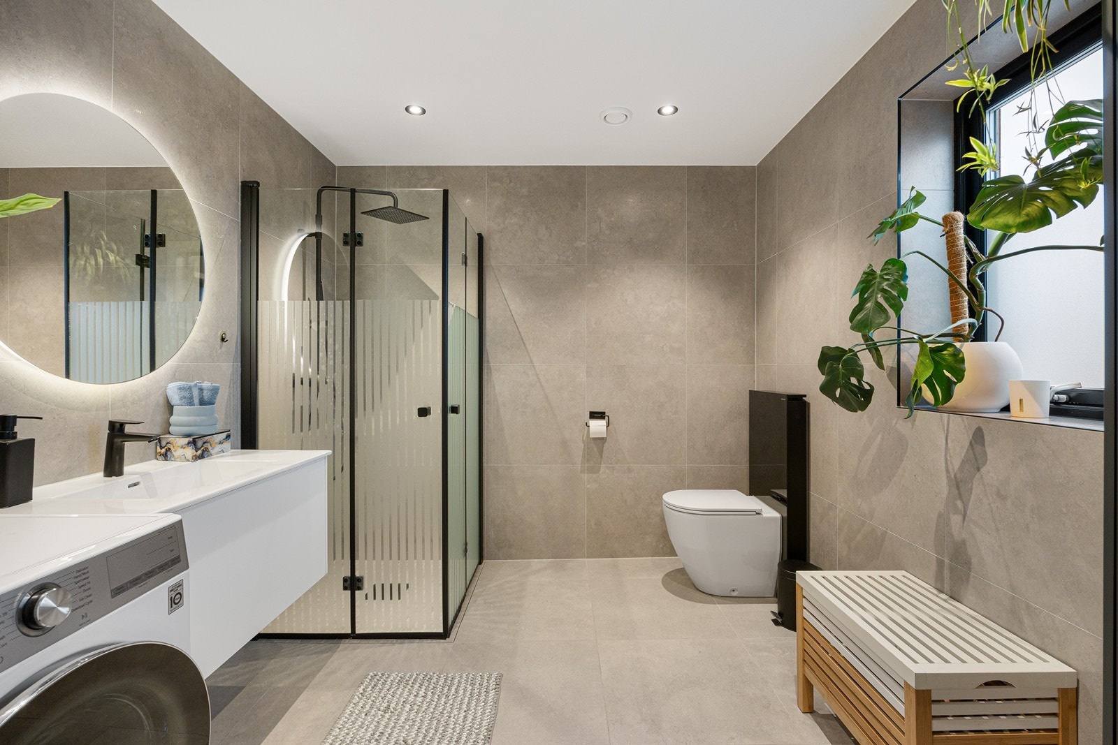 Opplegg for vaskemaskin er etablert, og badet har downlights, varmekabler og vegghengt toalett. Dushjørnet har et moderne design, med sort regnfallsdusj og innfellbare glassdører i sort innramming. Galleribilde