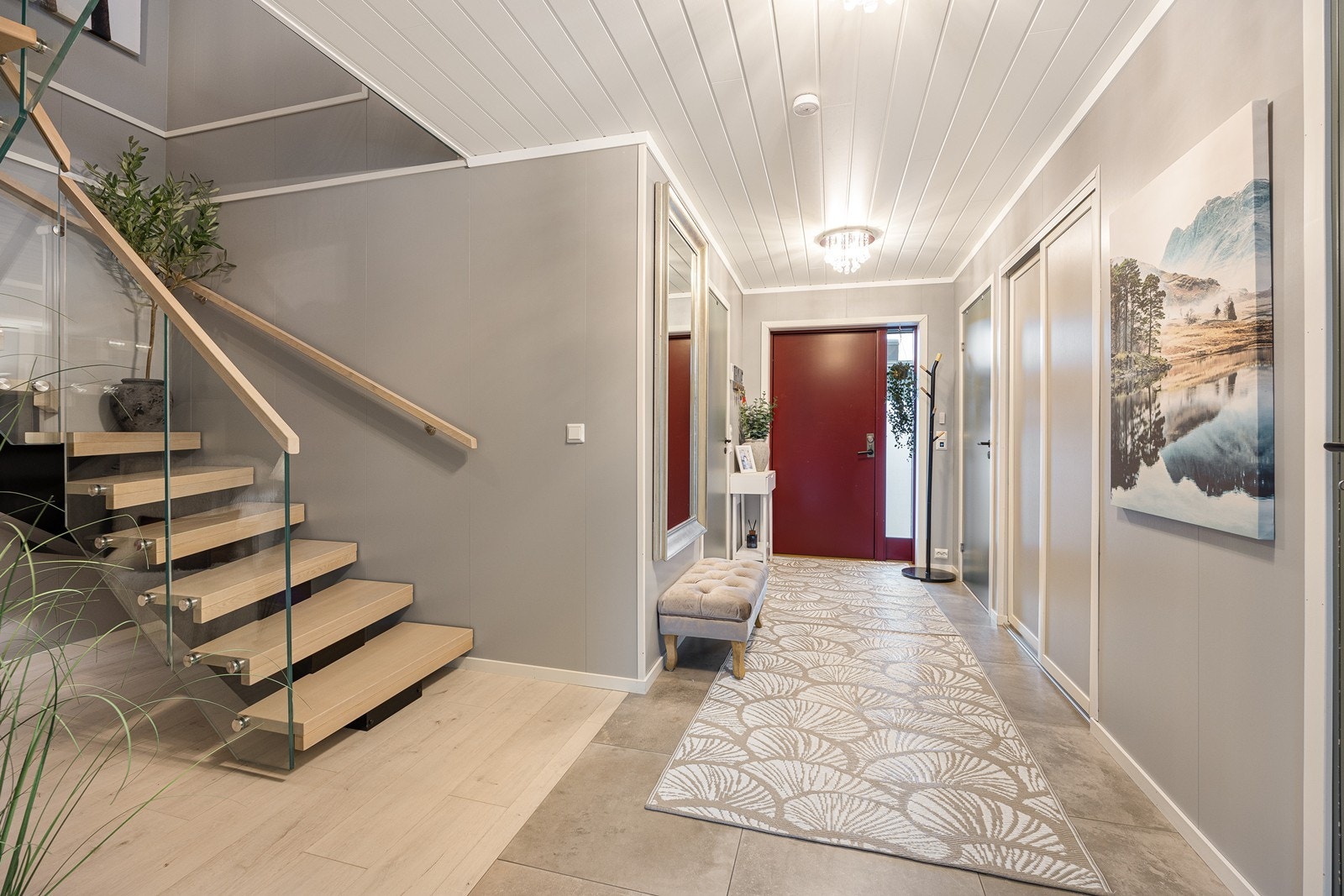 Varme er lagt under flisene, og entreen har god plass til å henge fra seg yttertøyet. Opp til 2. etasje er det en lakkert trettrapp med stilrent glassrekkverk. Galleribilde