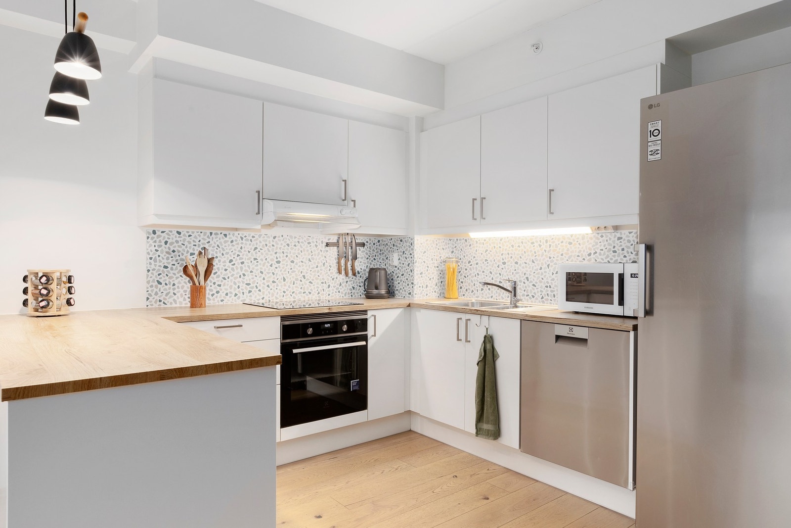 Moderne kjøkkeninnredning med glatte fronter, foliert benkeplate og delvis integrerte hvitevarer Galleribilde