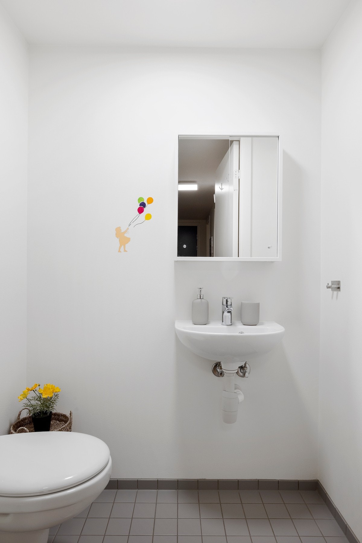 Praktisk toalett med fliser på gulv, innredet med toalett, servant og speilskap Galleribilde