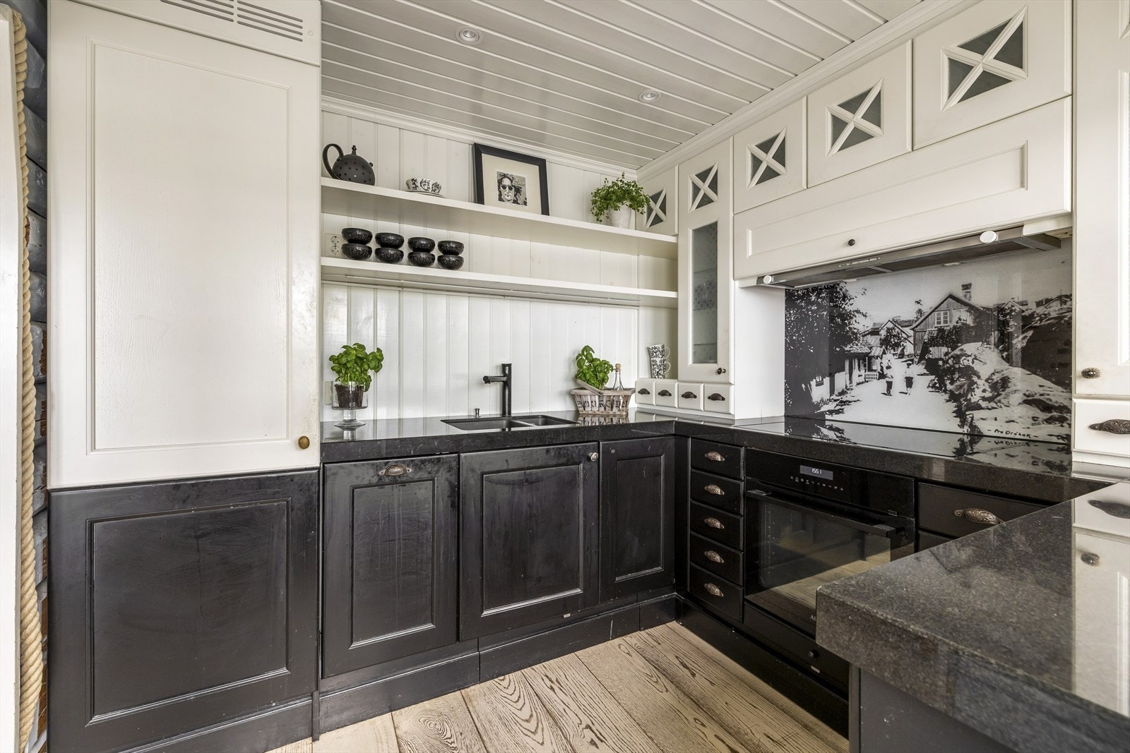 Kjøkkenet har en klassisk innredning med lyse overskap, hvor enkelte har glassdører, og sorte underskap med profilerte fronter. Galleribilde