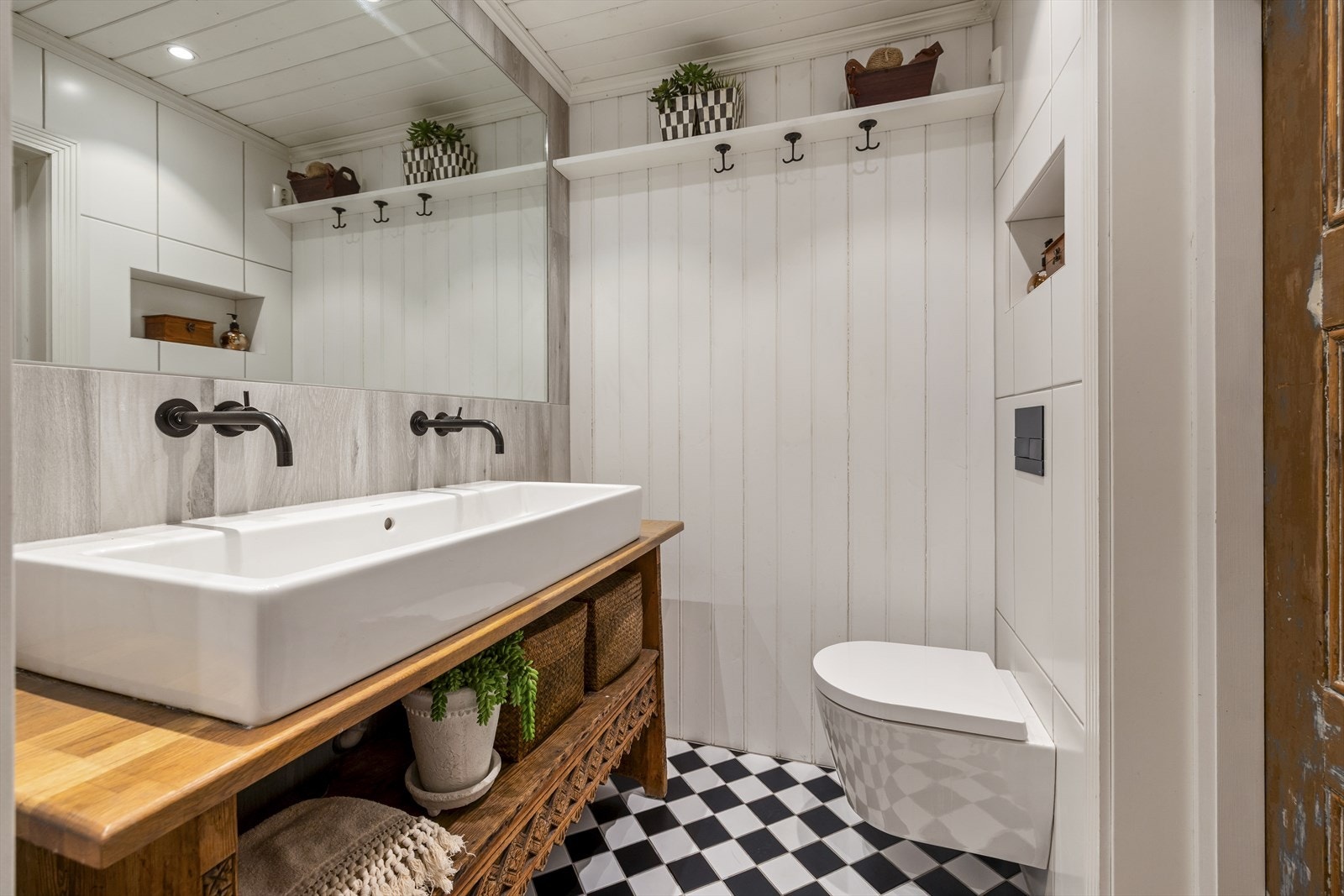 Veggene er kledd med fliser og malt panel, mens taket har malt panel og innfelte downlights som gir et varmt preg. Galleribilde