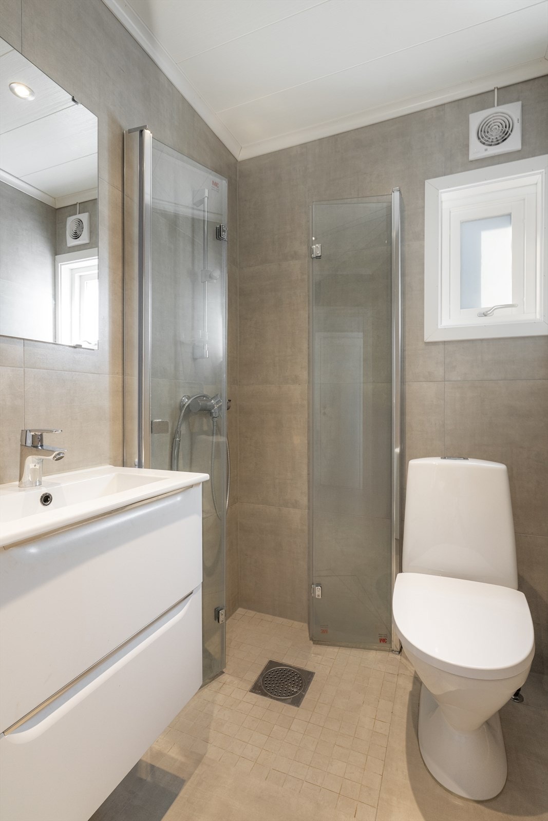 Det andre badet som også er et kombinert vaskerom er utført i samme stil som hovedbadet, med store moderne fliser og varme i gulvet. Galleribilde