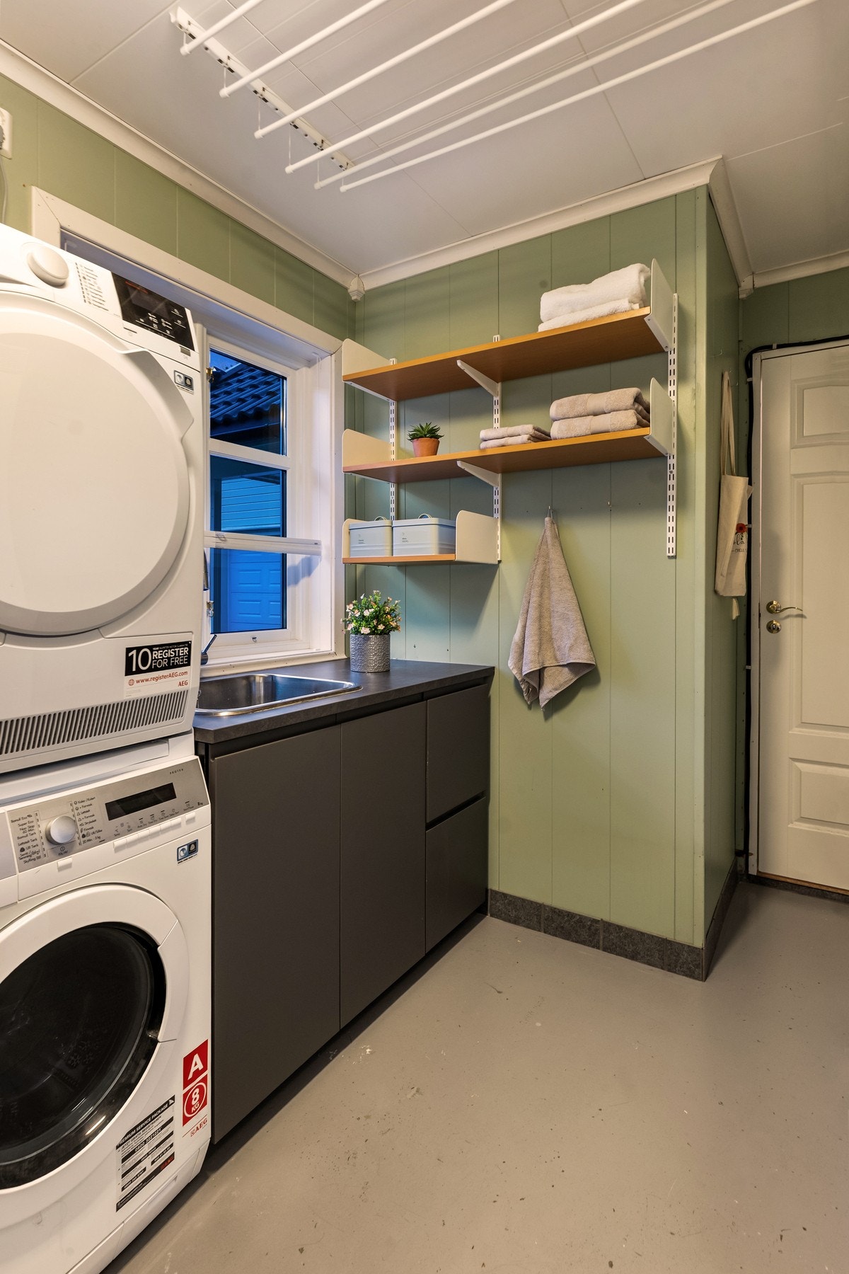 Praktisk vaskerom med benkeplate, skapplass og opplegg for vaskemaskin og tørketrommel. Galleribilde