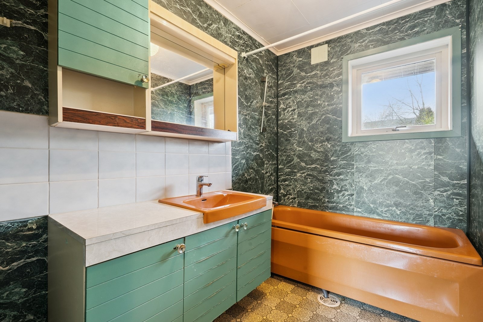 Retrobad med våtromsplater på vegger, belegg på gulv, servant i skapinnredning og badekar. Galleribilde