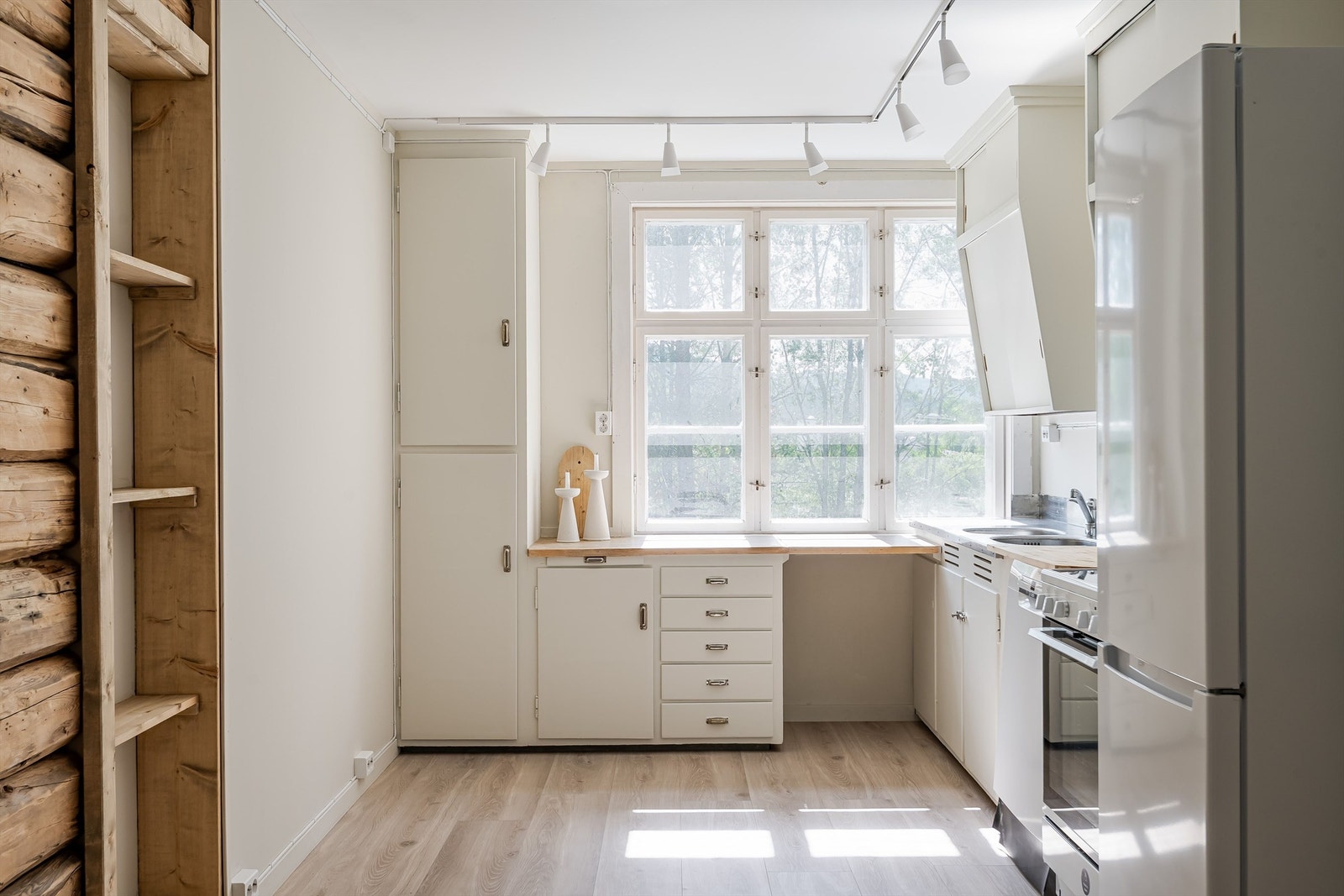 Kjøkkenet kombinerer funksjonalitet med en synlig tømmervegg. Galleribilde