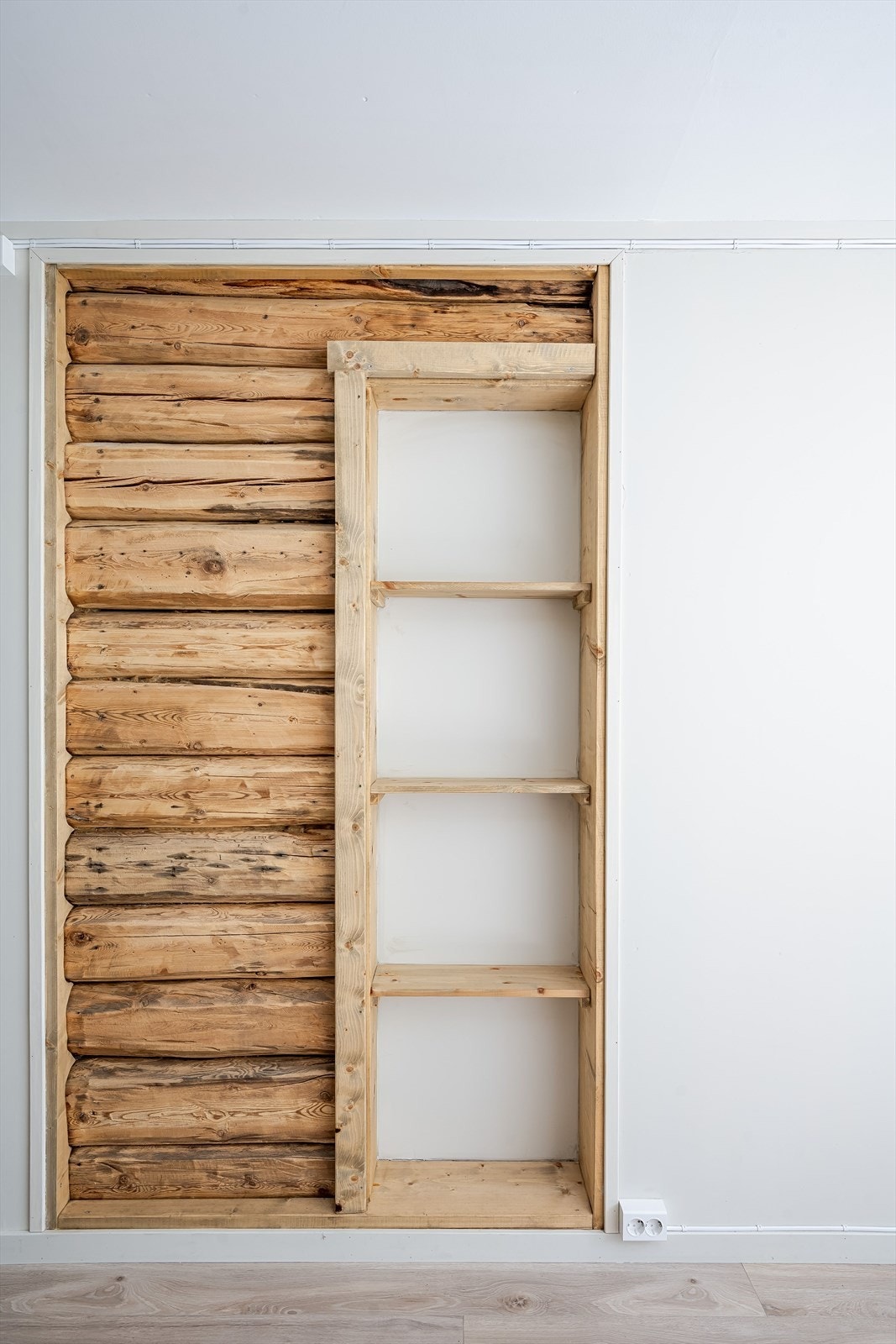 En eksponert tømmervegg med integrerte hyller gir en unik detalj. Galleribilde