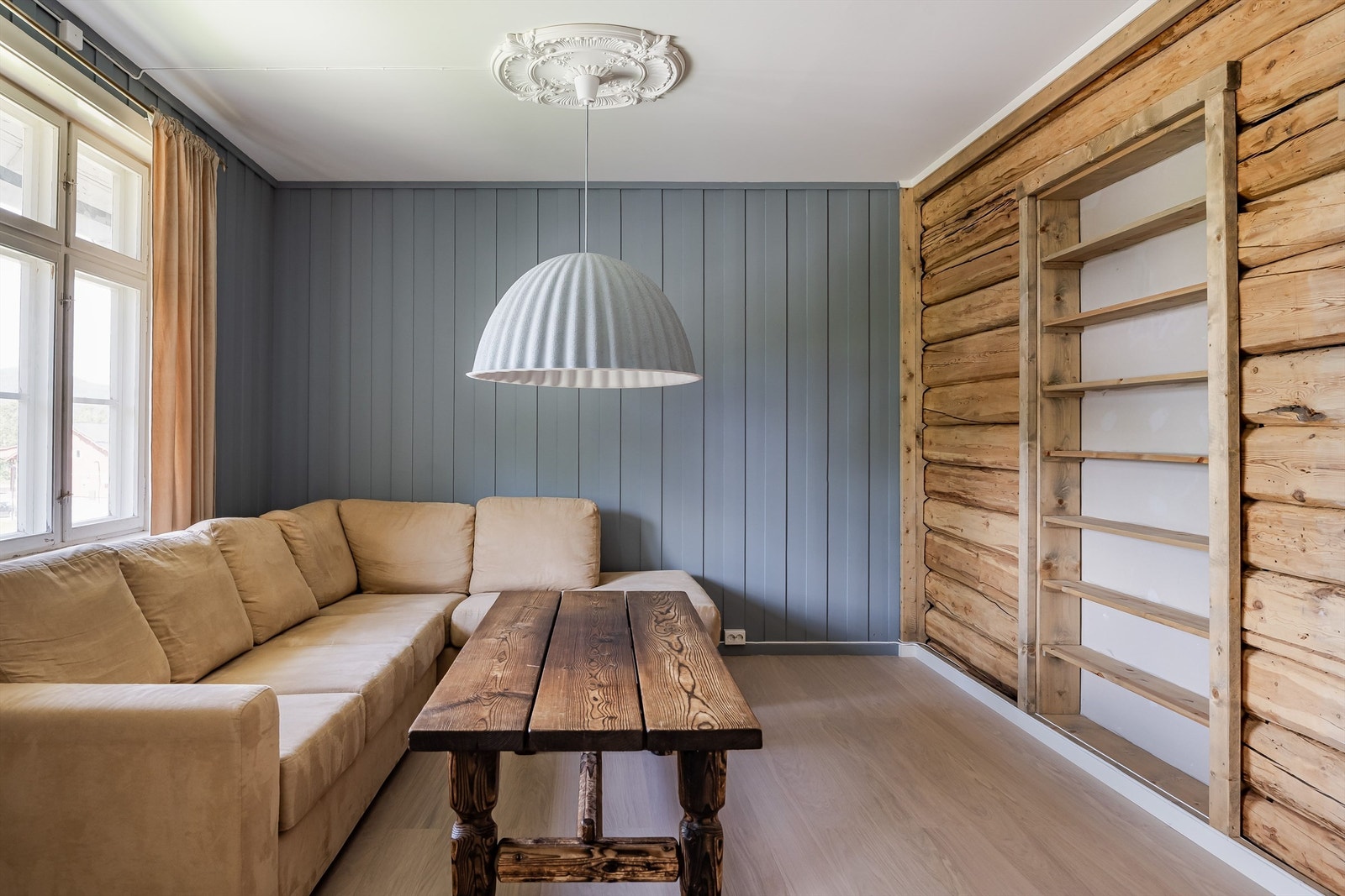 Den eksponerte tømmerveggen gir stuen en varm og rustikk karakter, et viktig bidrag til bevaring av kulturminne. Galleribilde